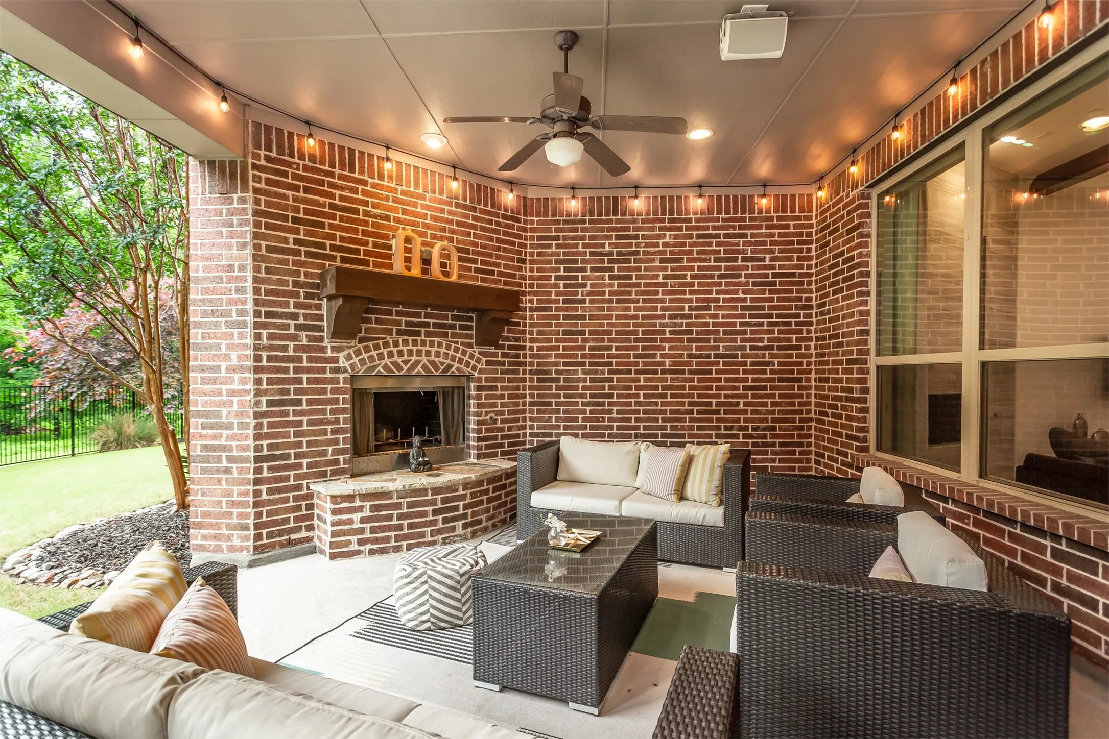 Covered patio featuring an outdoor fireplace with a wood mantle, brick surround, and a hearth