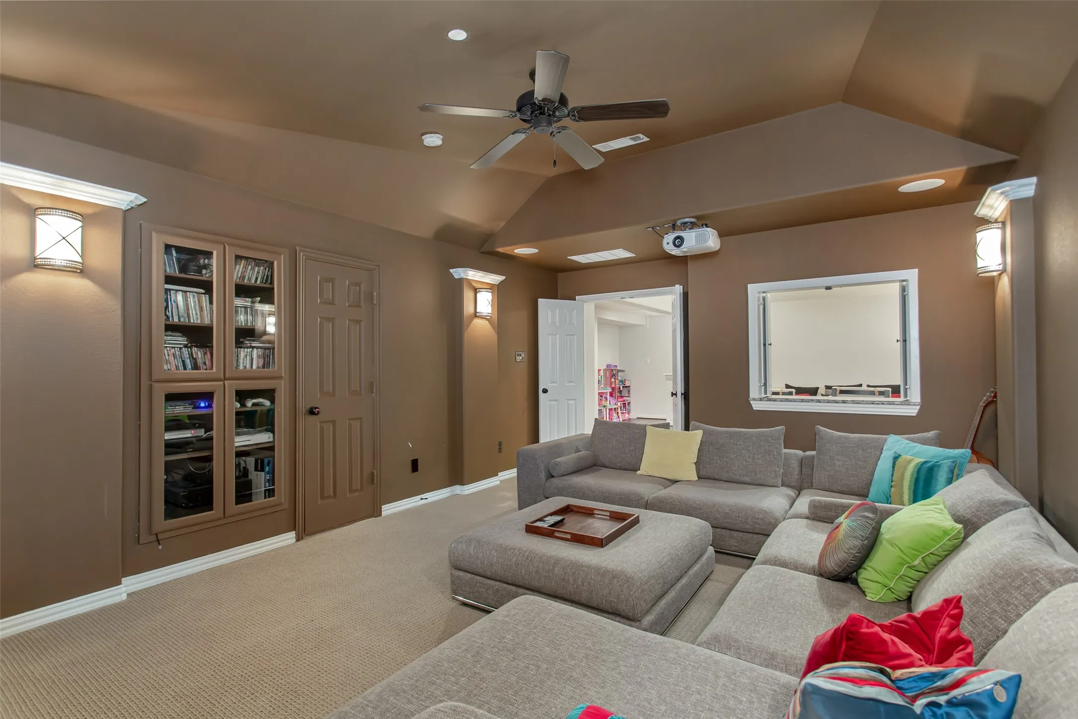 Media room featuring recessed lighting, a ceiling fan, a built-in projector, and wall sconces