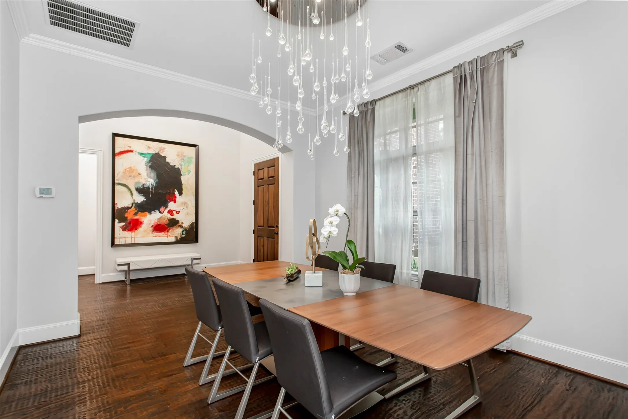 Dining area featuring a contemporary chandelier with glass elements, dark wood-finish flooring, and white baseboards