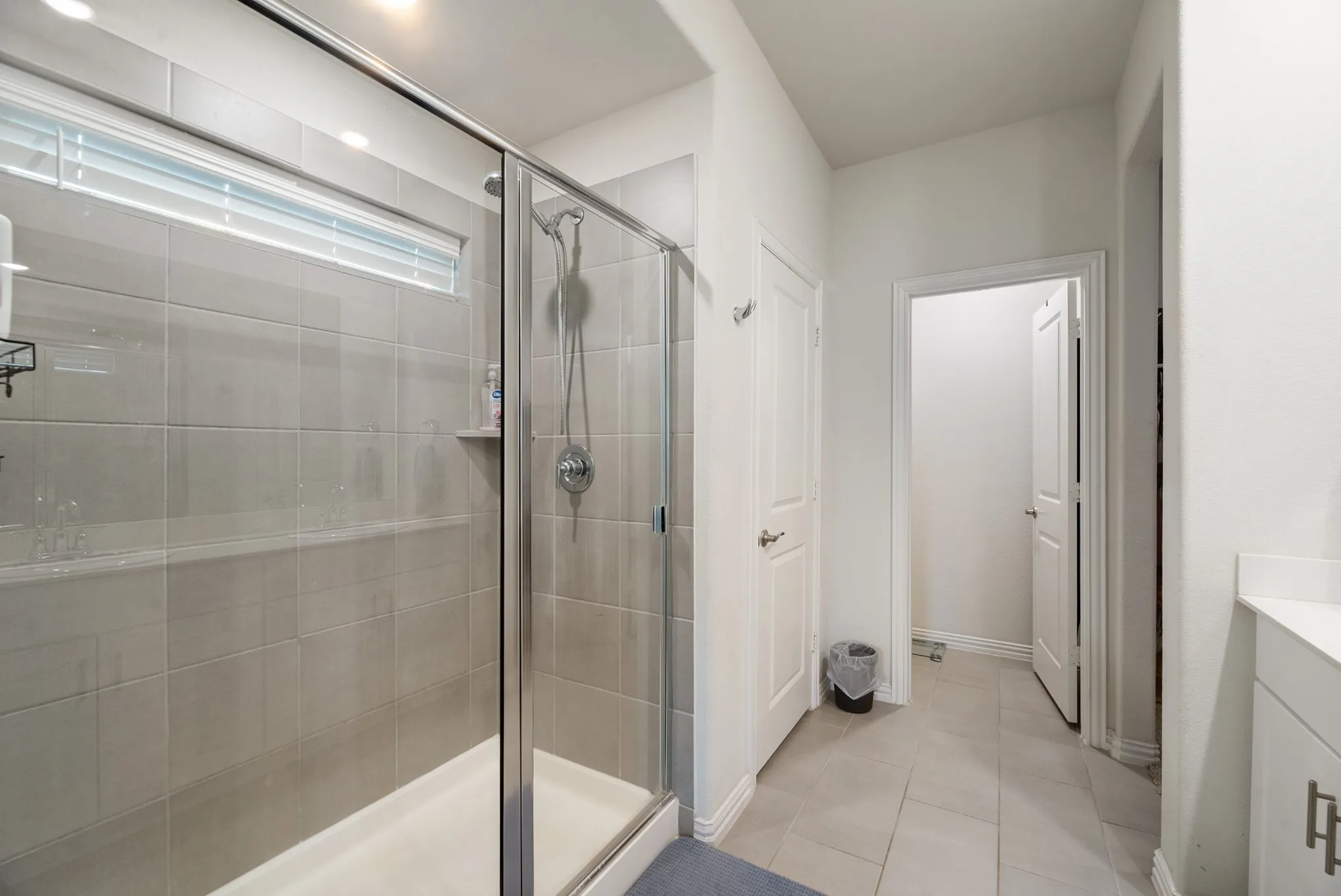 Walk-in shower featuring a glass enclosure, light-toned tile surround, and a fixed shower head