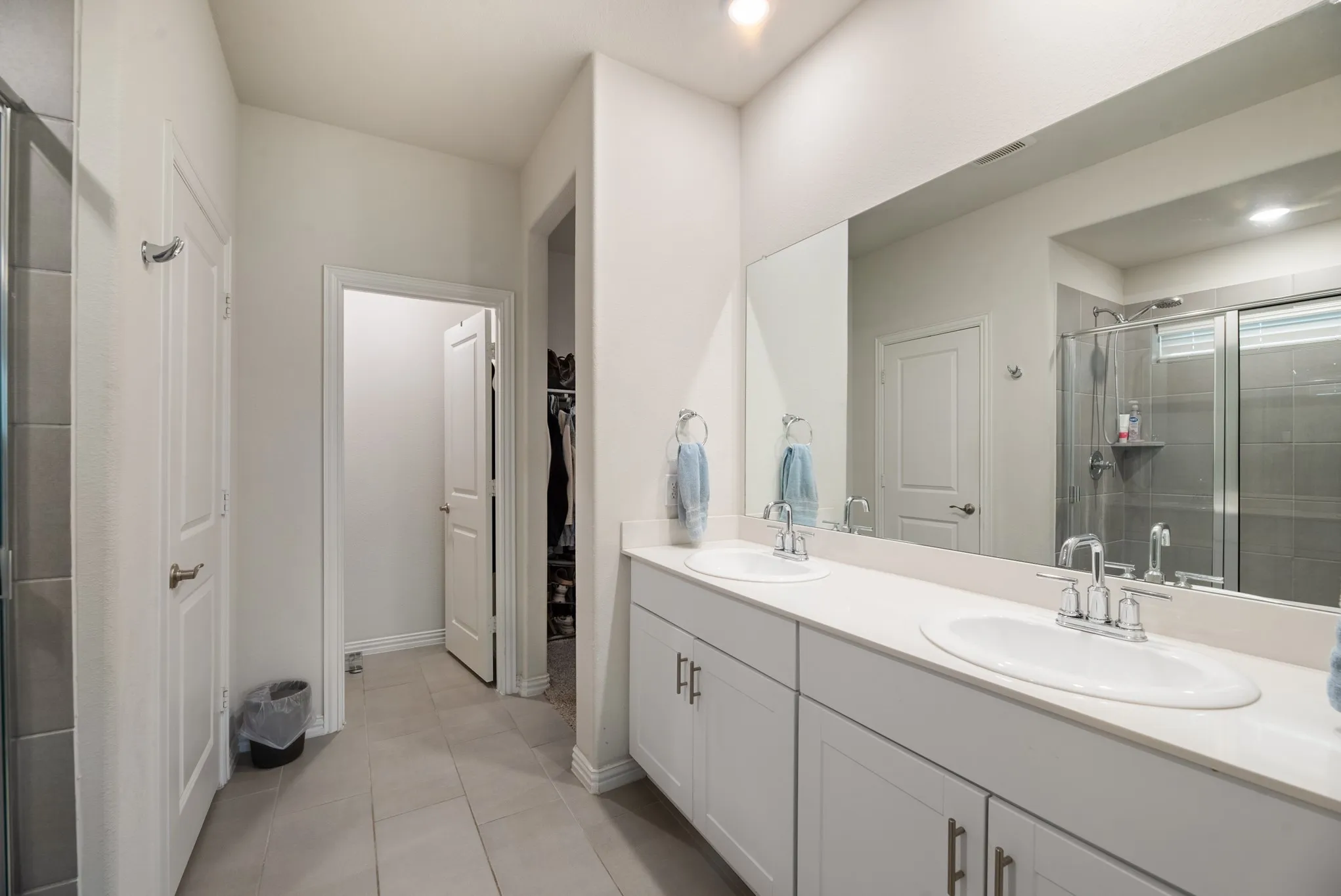 Dual vanity with solid surface countertop, white cabinetry, and undermount sinks