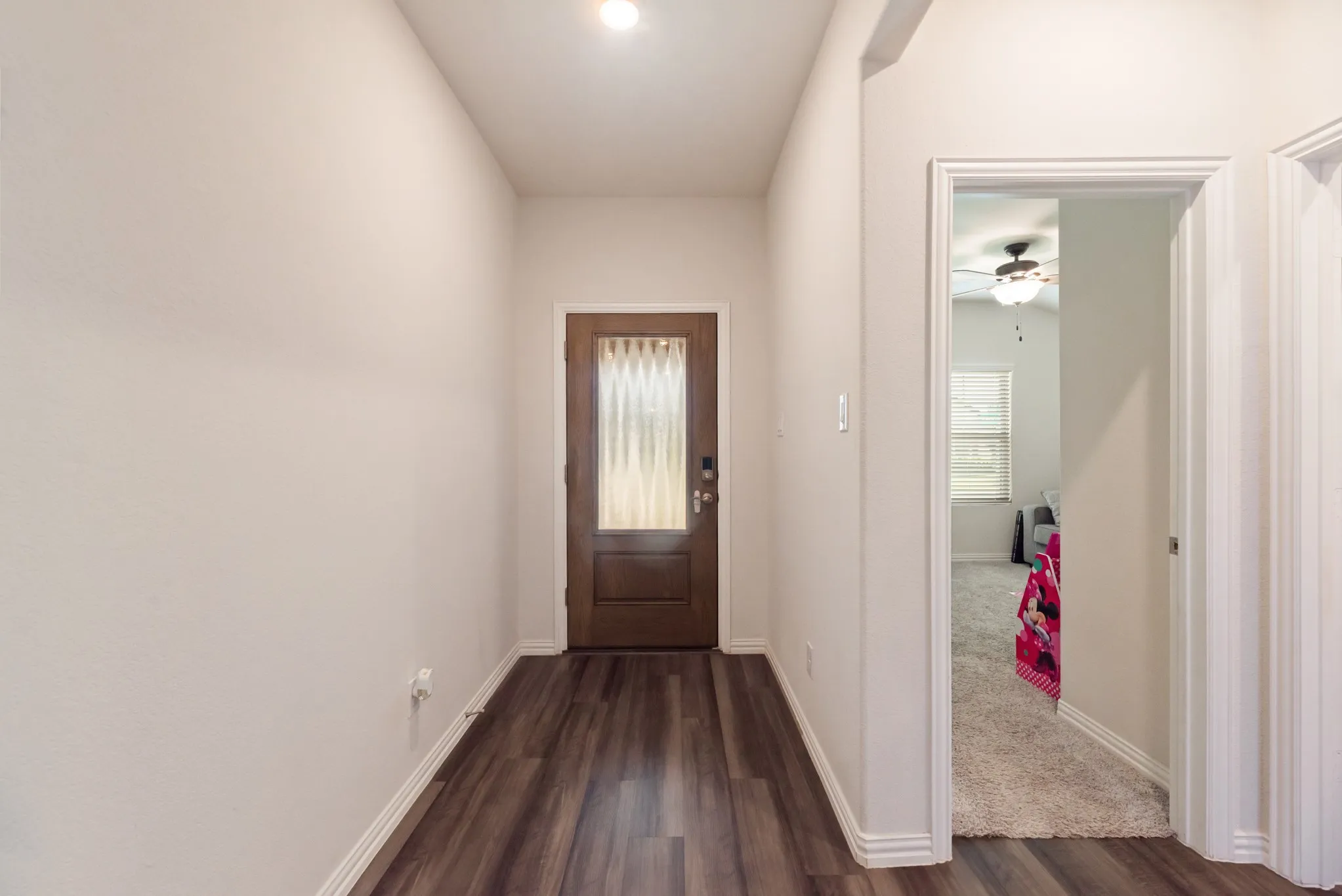 Entryway featuring wood-finish flooring, a solid wood door with glass paneling, and white baseboards