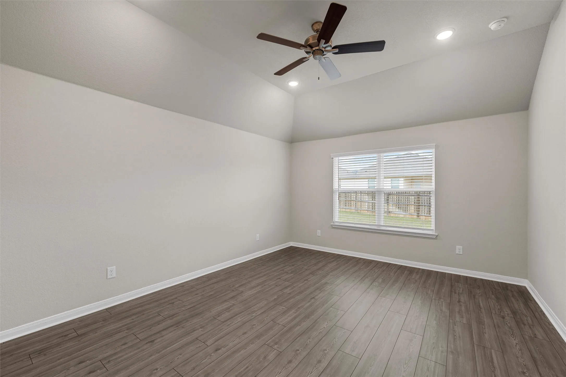 Room featuring vaulted ceilings, wood-finish flooring, recessed lighting, a ceiling fan, and a double-pane window with blinds