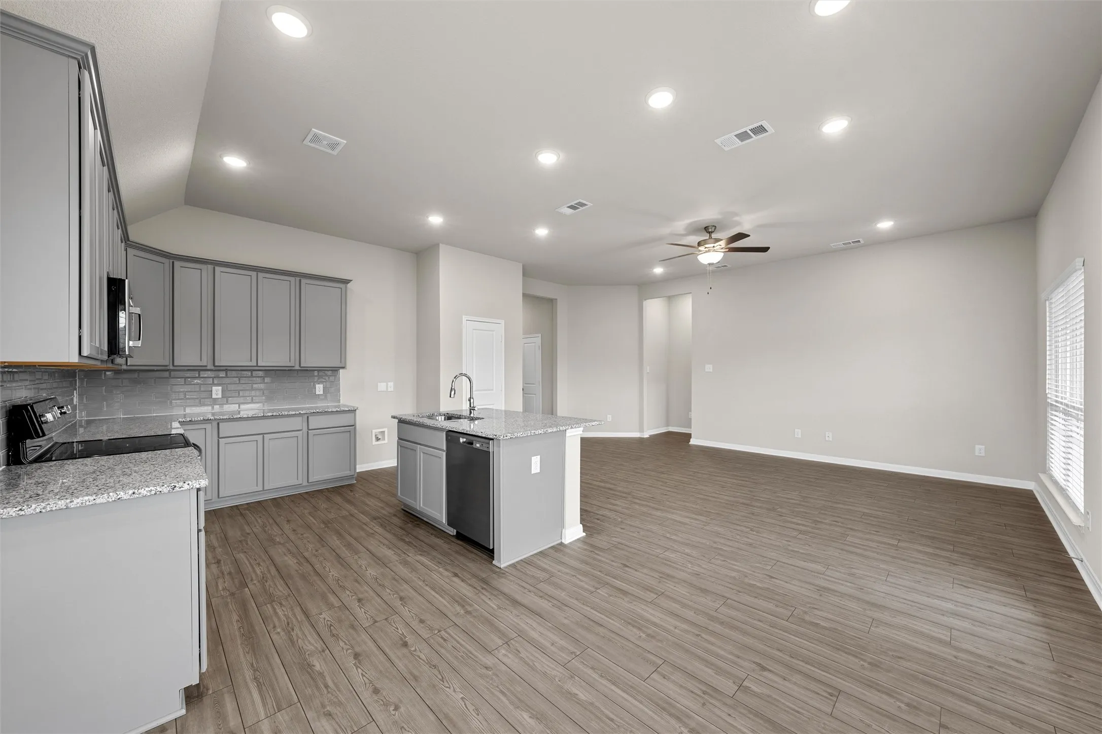 Open-concept living area featuring wood-finish flooring, a contemporary ceiling fan, and recessed lighting