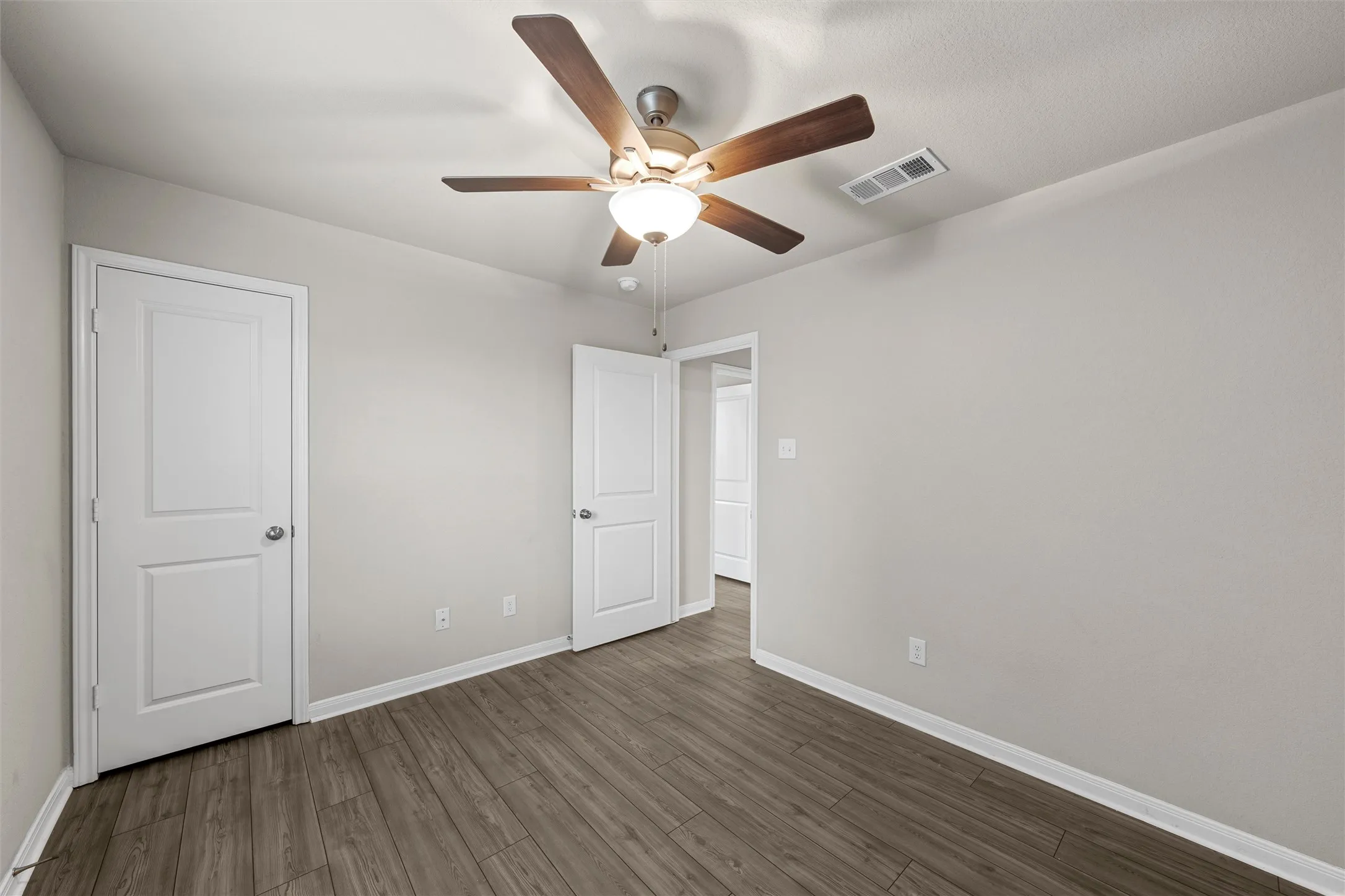 Interior room with wood-finish flooring, light gray wall paint, and white baseboards