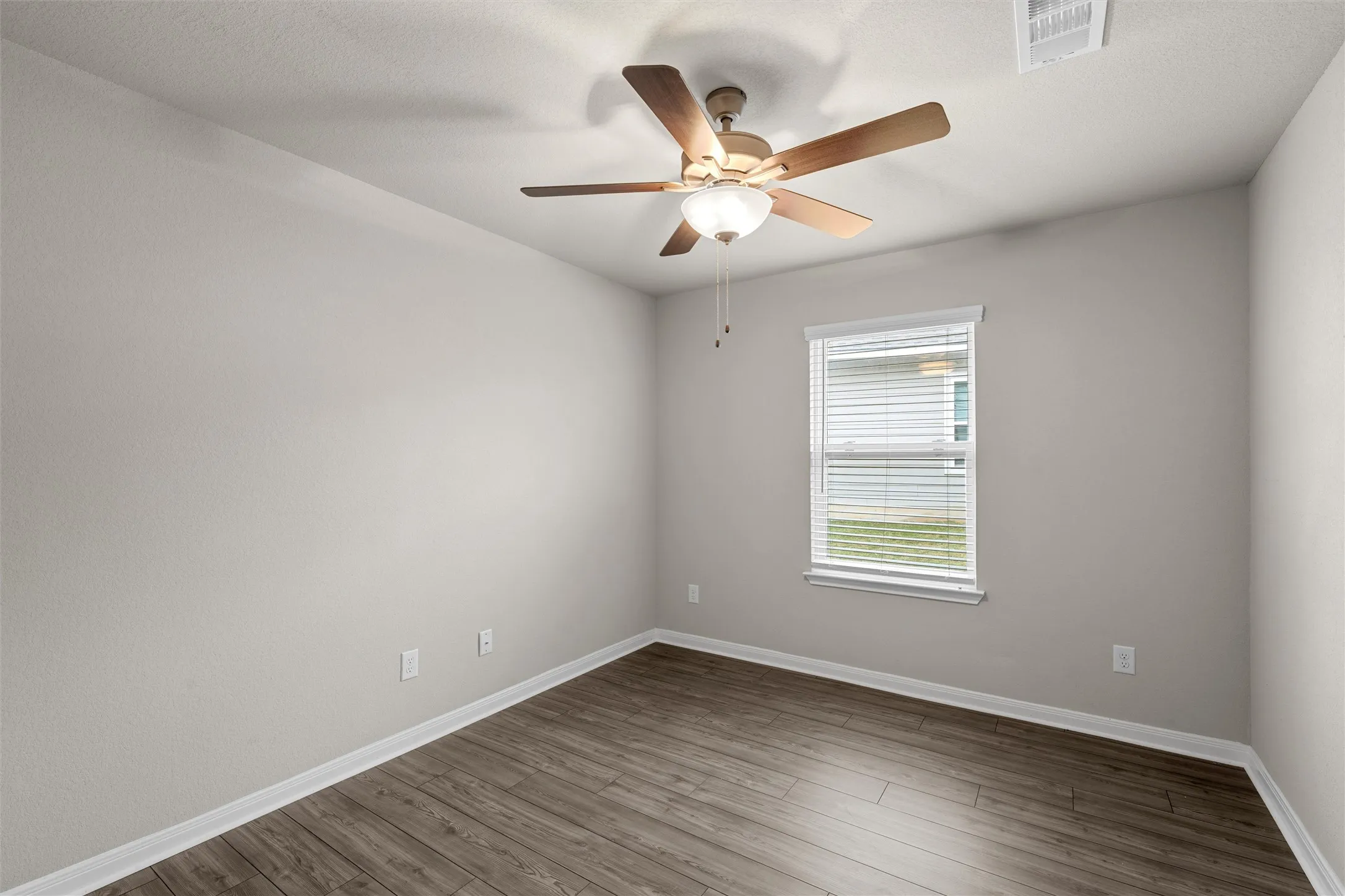 Room featuring wood-finish flooring, light grey painted walls, and white baseboards