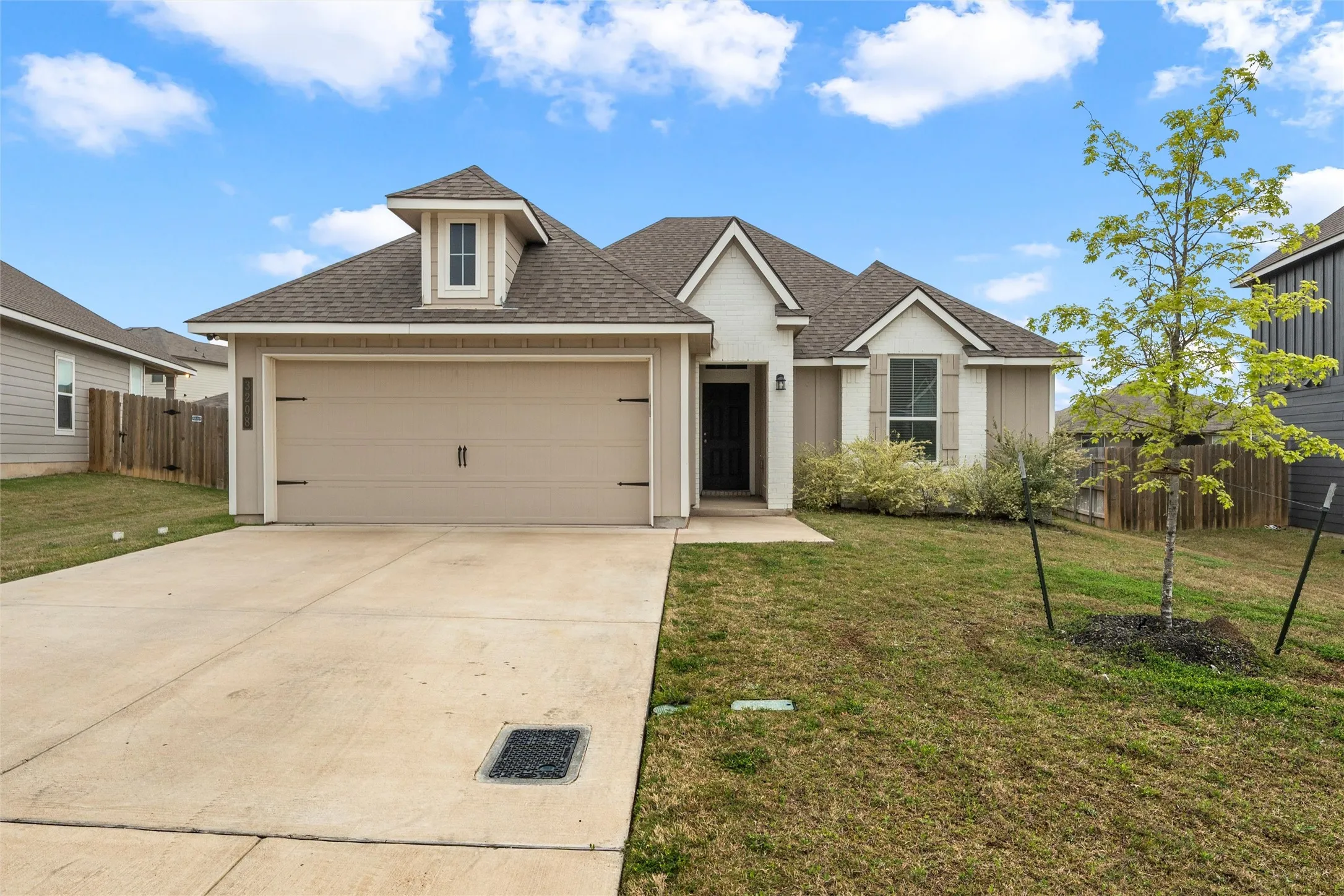 Contemporary single-story residence featuring a two-car garage with decorative hardware, a dormer window, and a gabled roofline