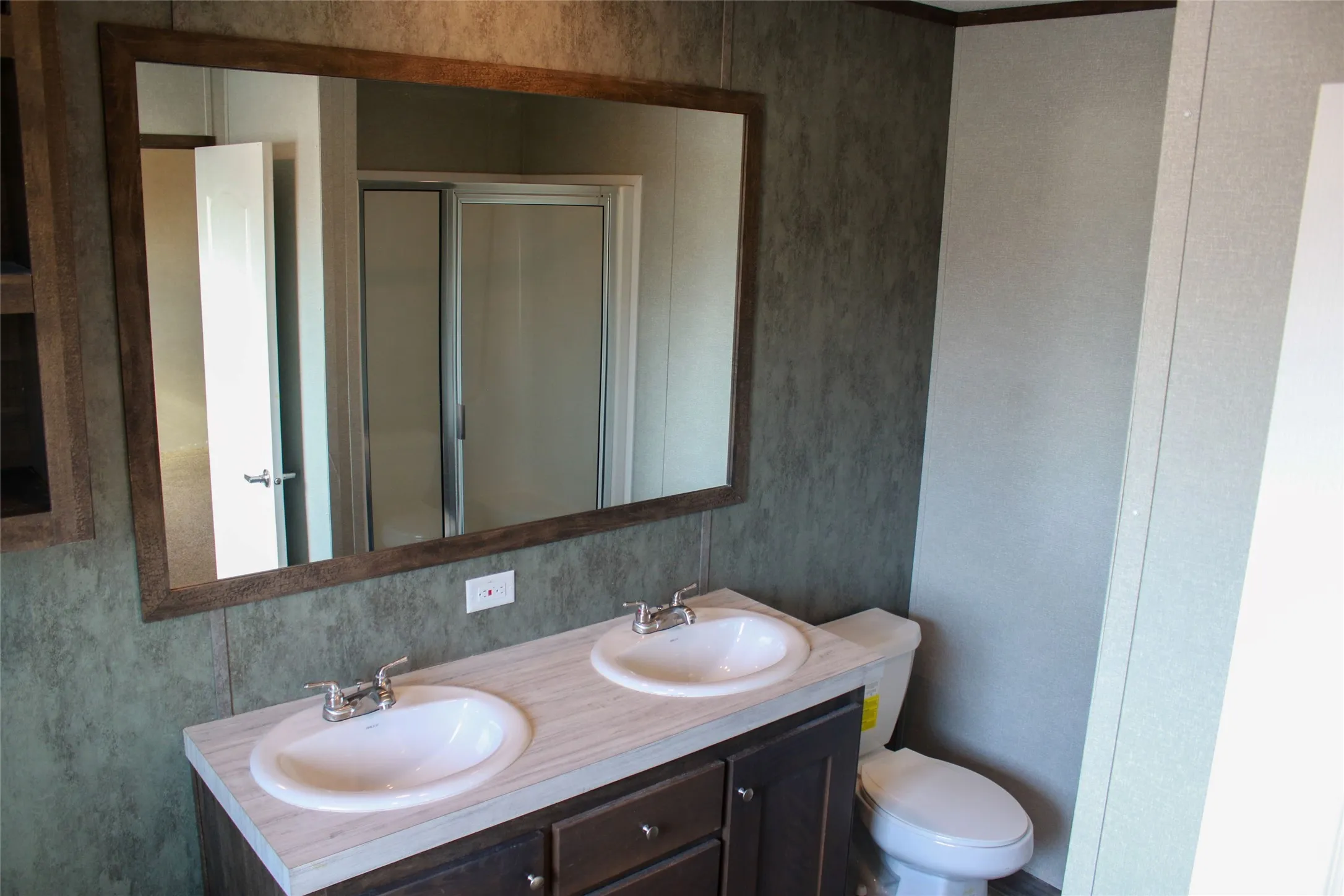 Dual vanity with undermount sinks and chrome fixtures, dark wood-finish cabinetry, and a large framed mirror