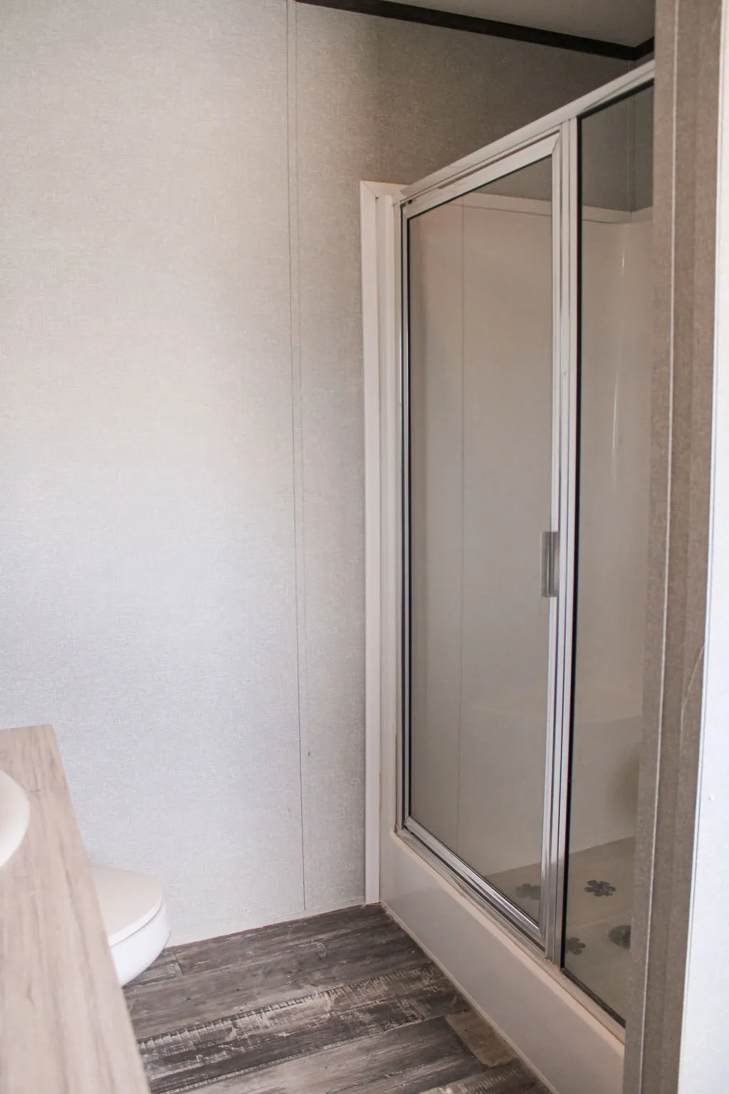 Enclosed shower featuring a sliding glass door and white base
