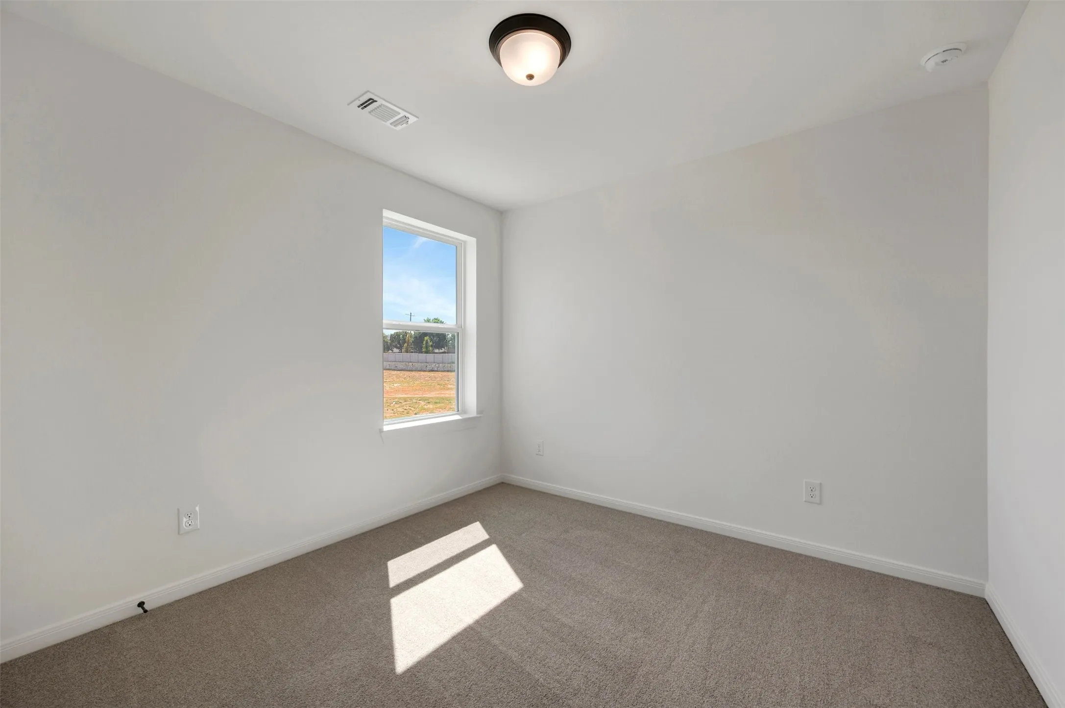 Neutral-toned carpet flooring, white painted walls, single window, flush mount ceiling light fixture