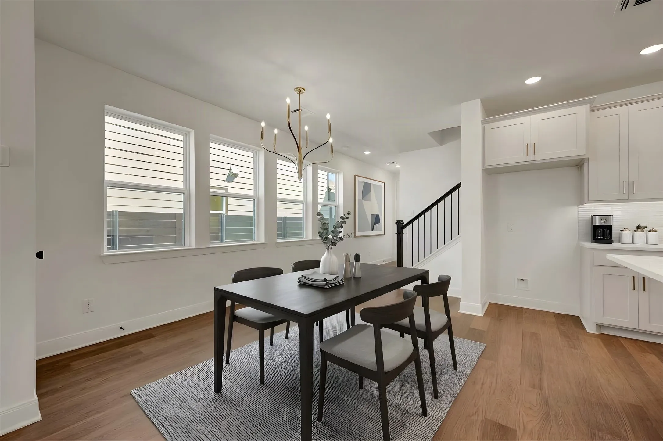 Dining area featuring wood-finish flooring, a contemporary chandelier, and a wall of multiple windows