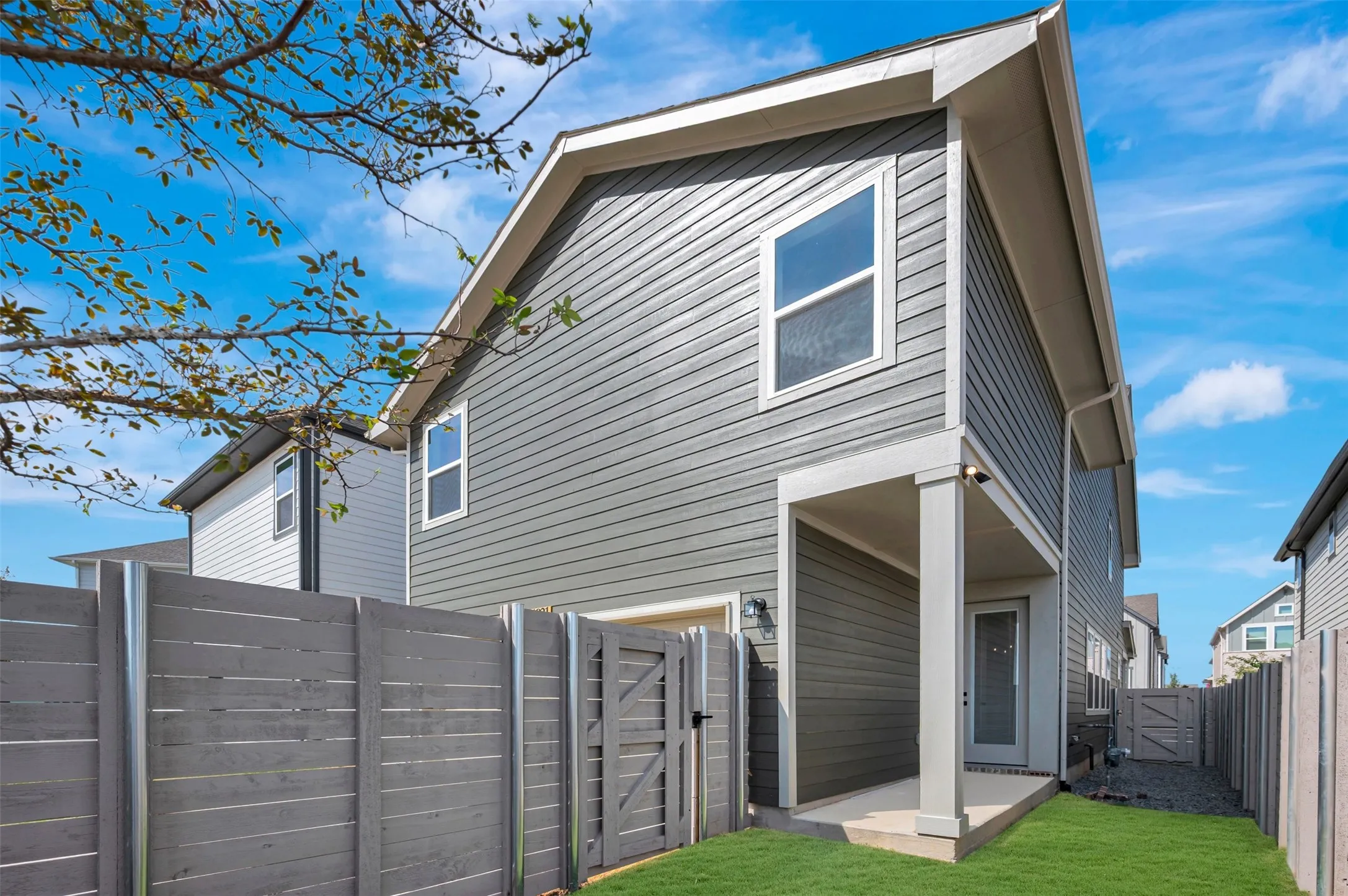 Two-story exterior with horizontal siding, covered patio, privacy fencing, and a side yard