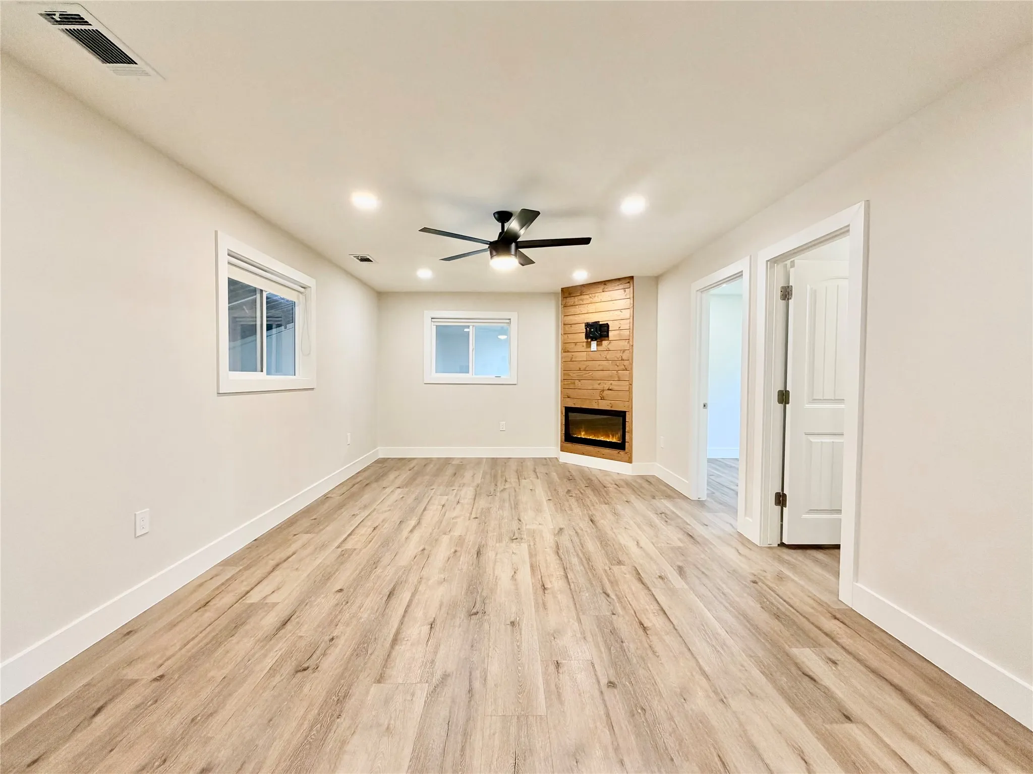 This bright, open-concept living area features gorgeous wood-look flooring, recessed lighting, and a modern ceiling fan to keep the space breezy year-round.