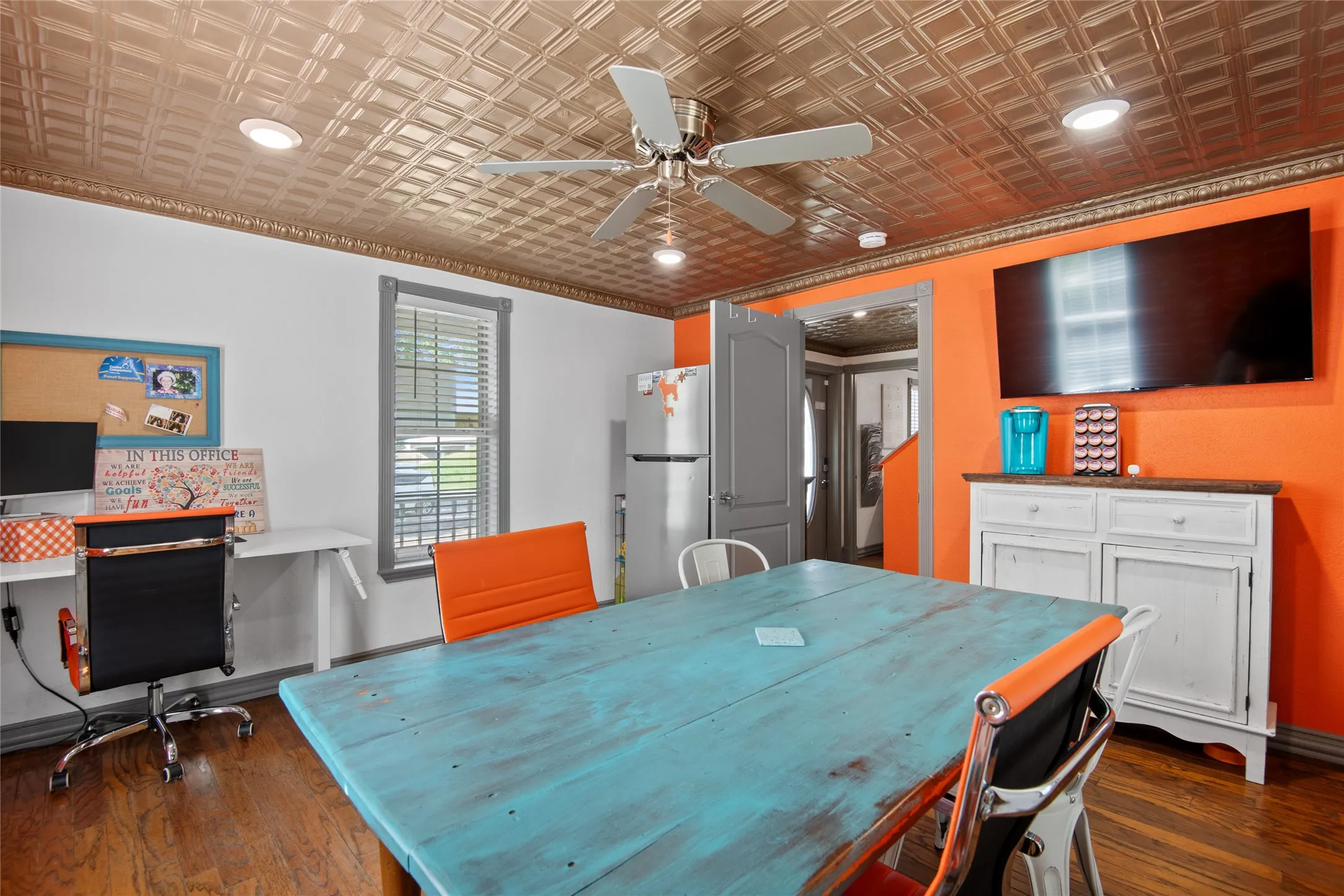 This versatile room downstairs features hardwood floors, a textured ceiling with recessed lighting and a ceiling fan, and a window with blinds