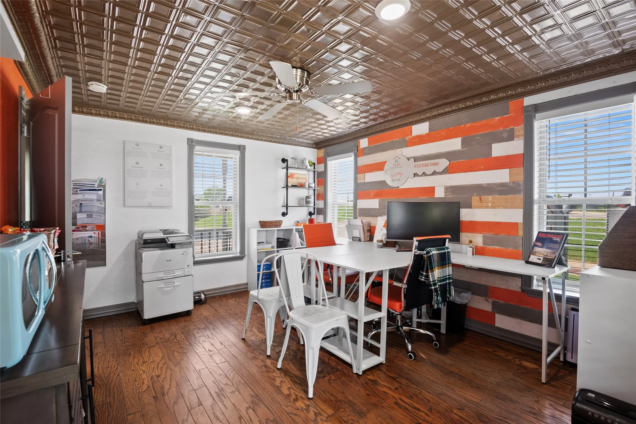 Versatile room, with private entrance, featuring hardwood floors, a decorative ceiling with a ceiling fan, and an accent wall with a wood plank design.