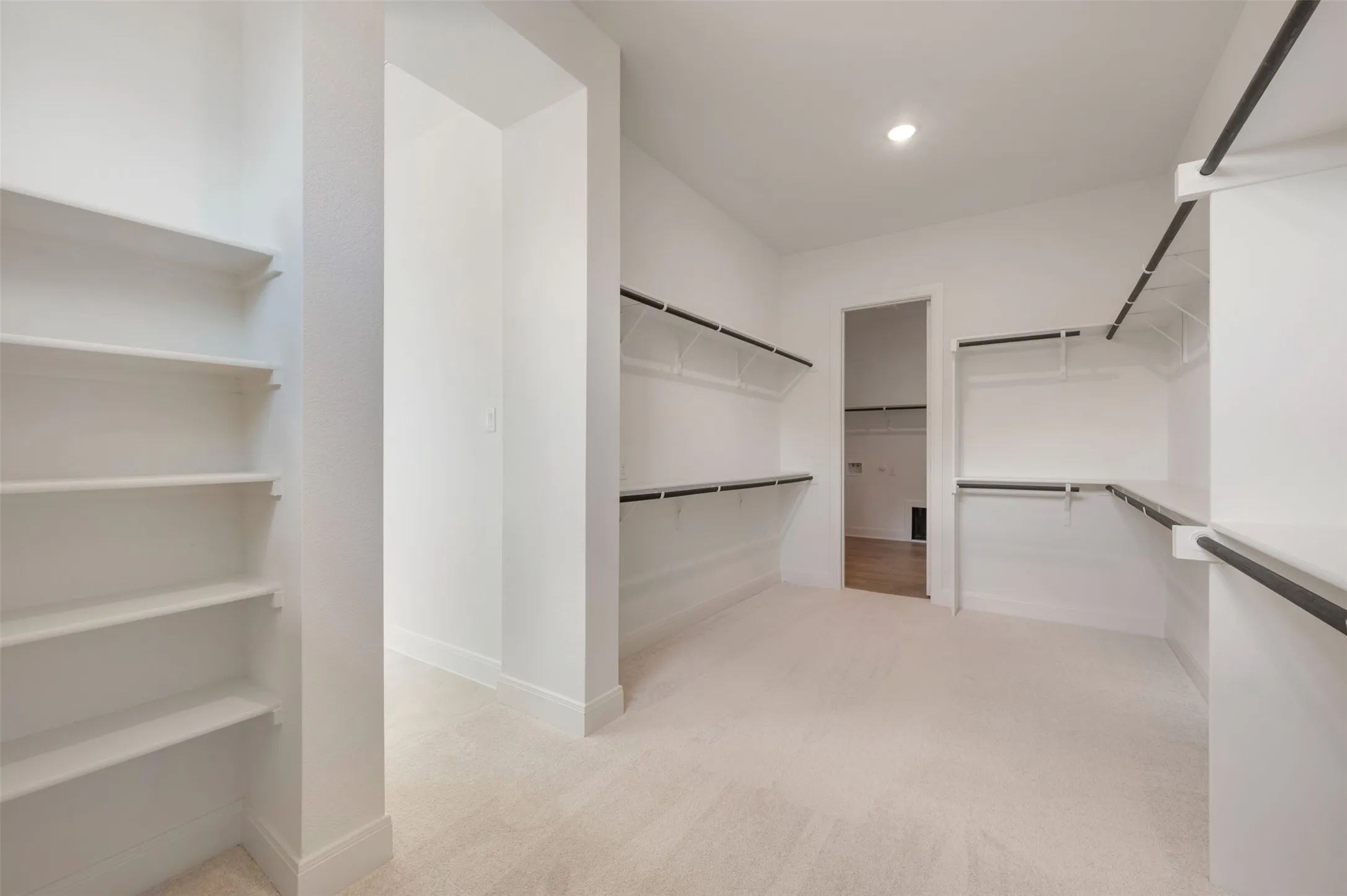 Expansive closet space featuring built-in shelving, hanging rods, recessed lighting, and light-toned carpet