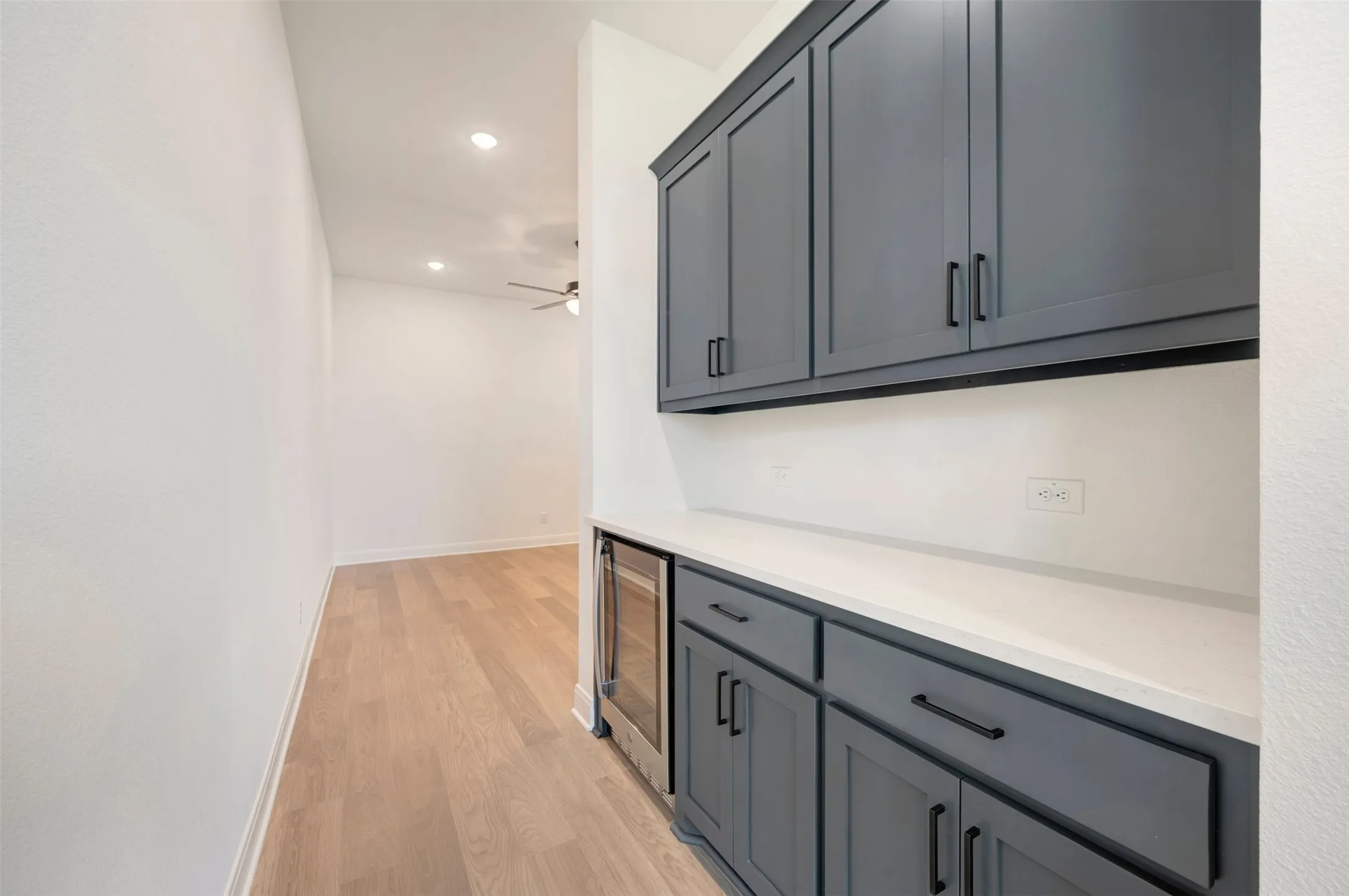 Built-in cabinetry with matte black hardware, white countertop, integrated beverage refrigerator, and recessed lighting