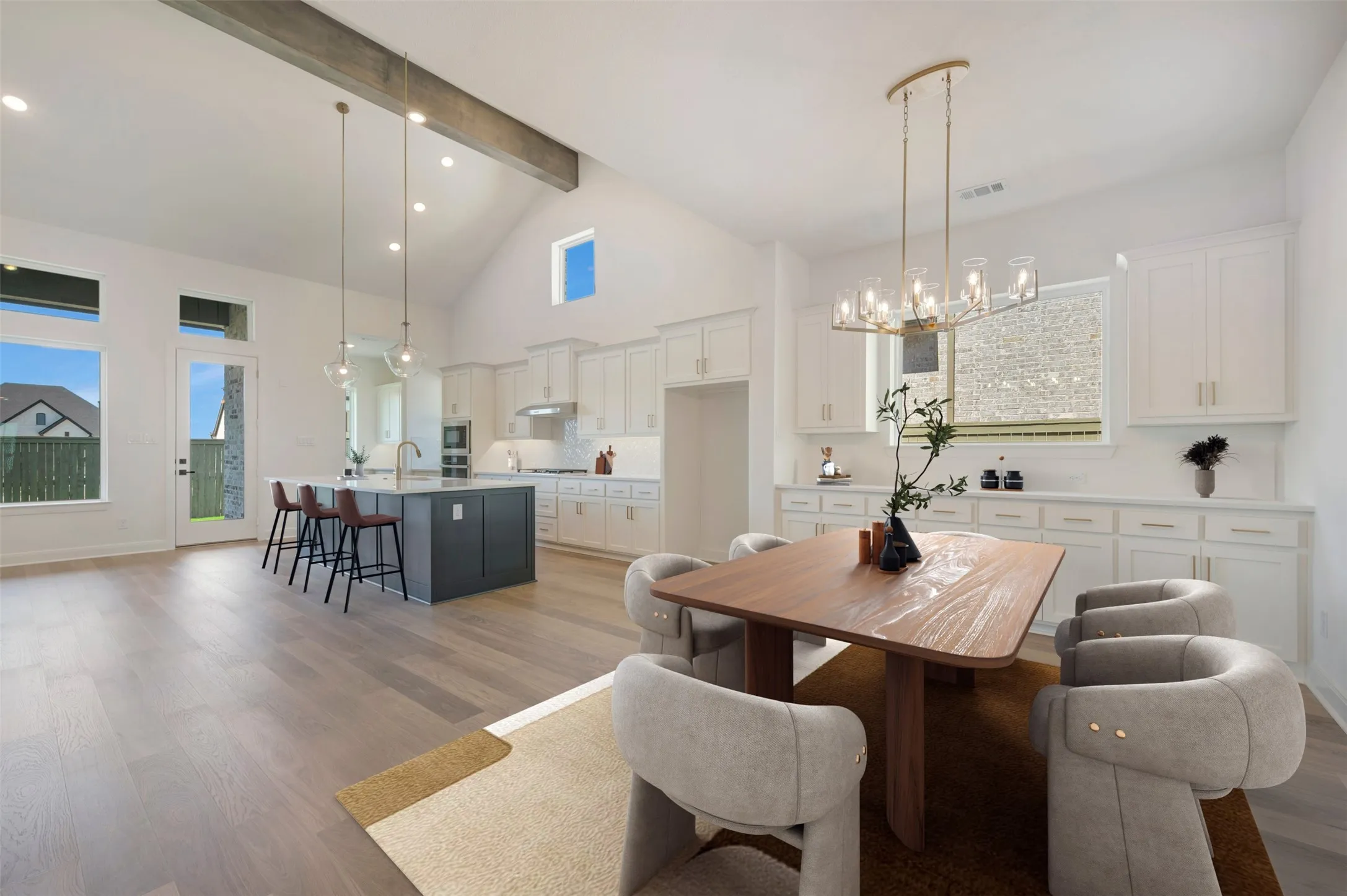 Open-concept living space with vaulted ceilings, exposed beam accent, and wood-finish flooring