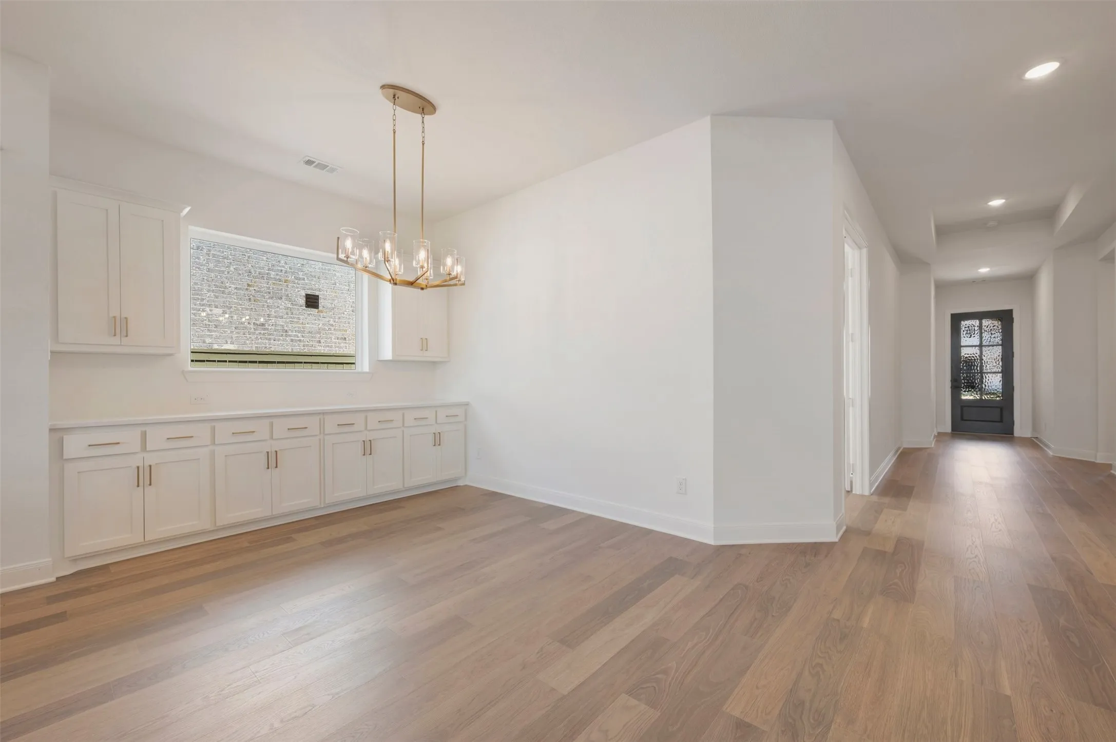 Open-concept interior featuring wood-finish flooring, recessed lighting, and a modern chandelier