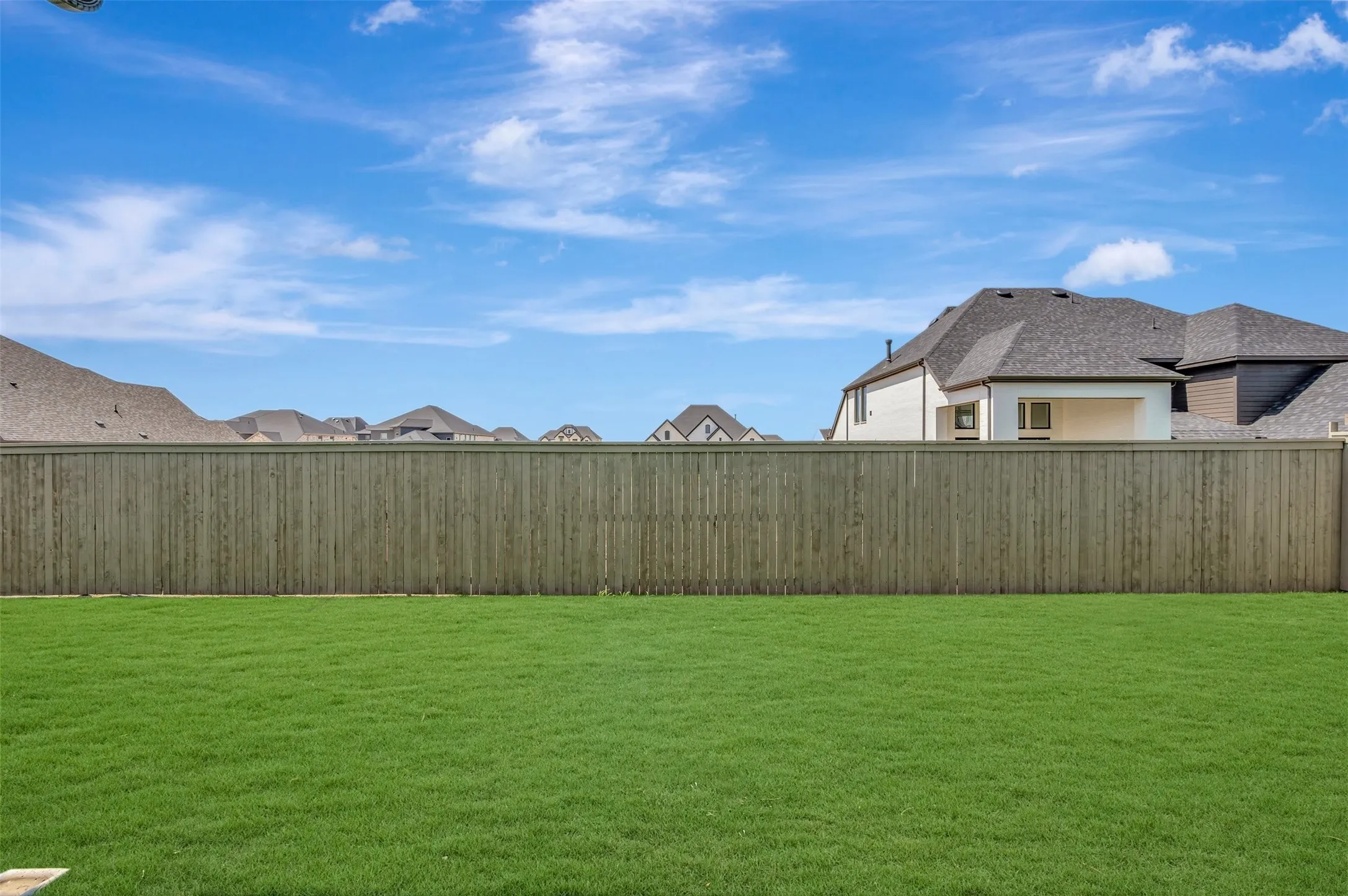 Expansive backyard featuring a manicured lawn and a privacy fence