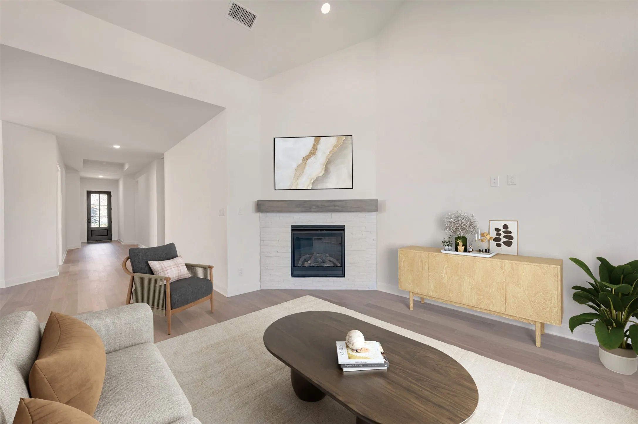 Vaulted ceiling, corner fireplace with white brick surround, wood mantel, and wood-finish flooring