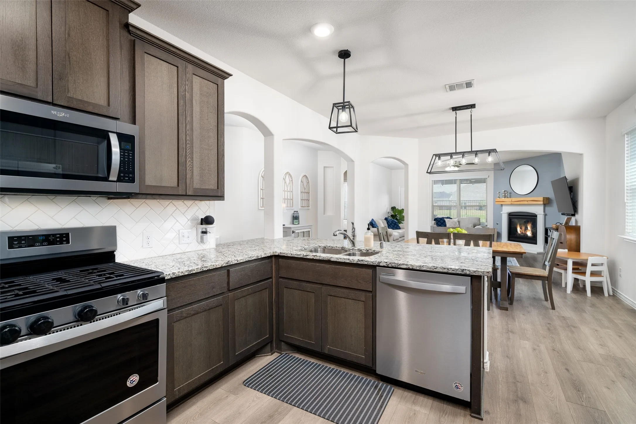 Stainless Gas Range, Microwave, and View to Dining and Living Spaces.