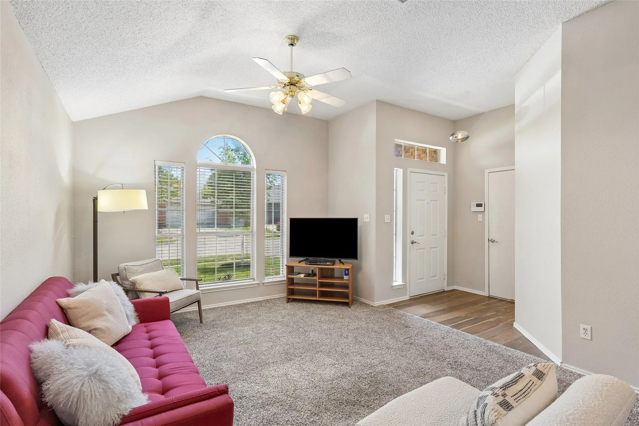 Living room with large windows, semi-vaulted ceiling, light color walls and carpet recently cleaned.