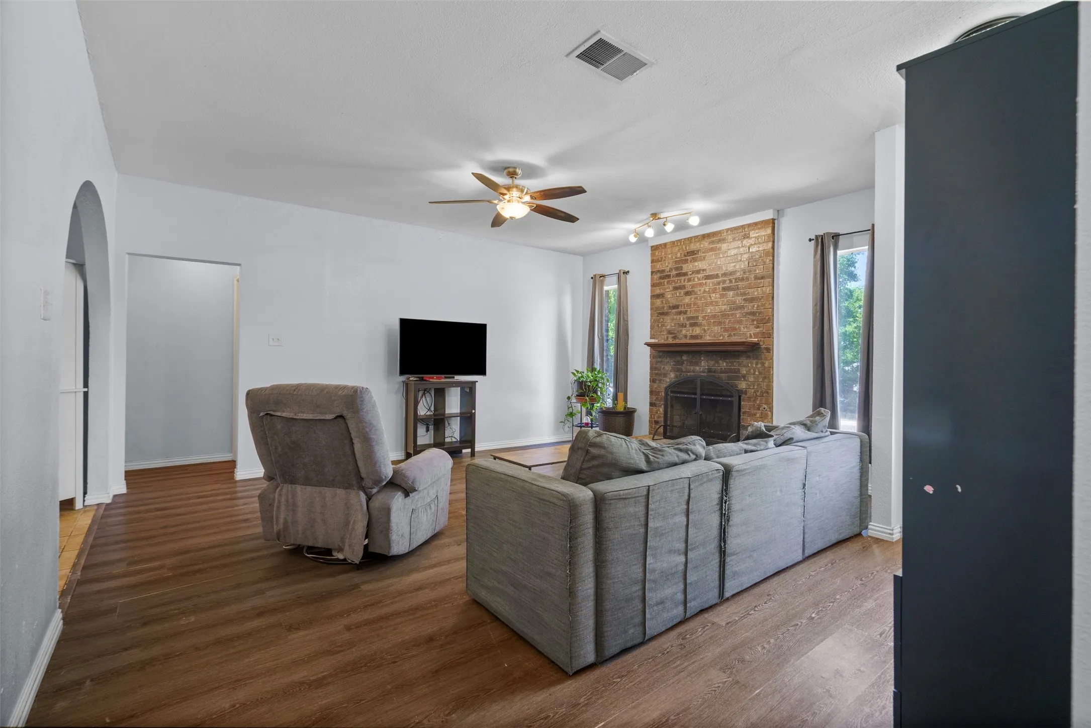 Spacious living area featuring wood-finish flooring and a ceiling fan