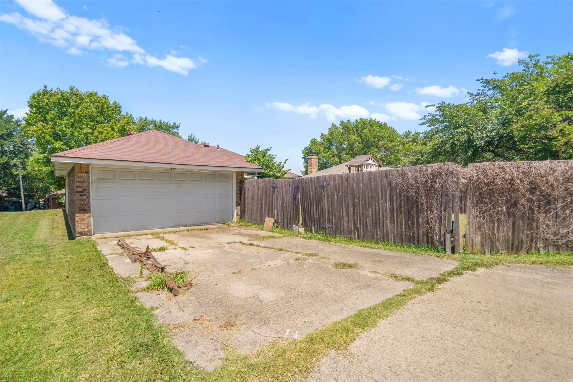Attached two-car garage with a concrete driveway, brick exterior, and shingled roof