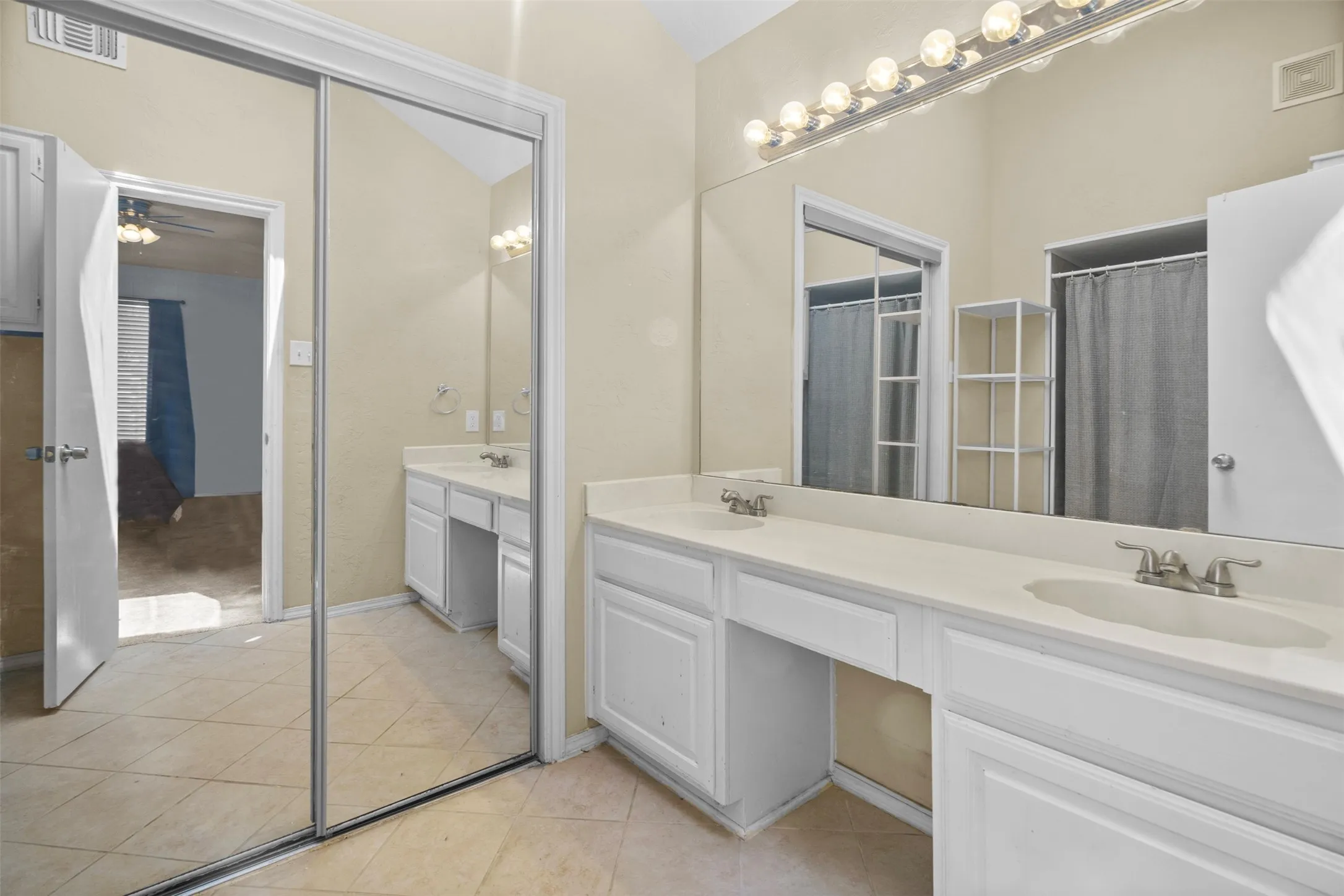 Bathroom featuring a double vanity with white cabinetry, light-toned countertops, and dual integrated sinks