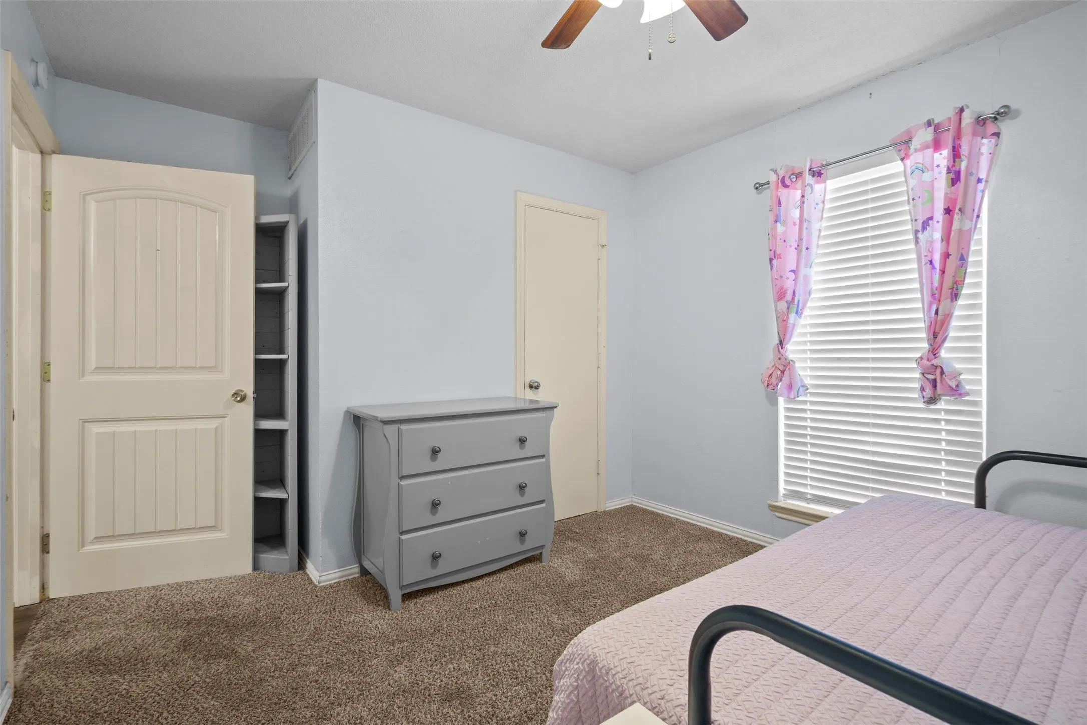 Carpeted room featuring a ceiling fan, a window with blinds, and an open closet with built-in shelving