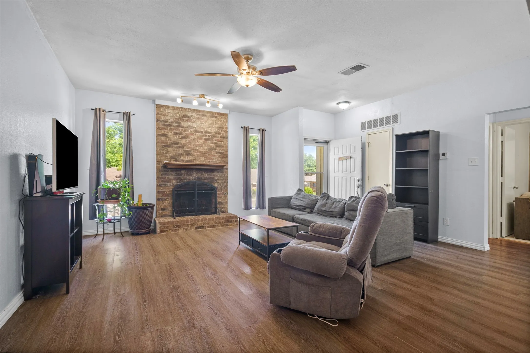 Living area featuring wood-finish flooring and a brick-faced fireplace with a hearth