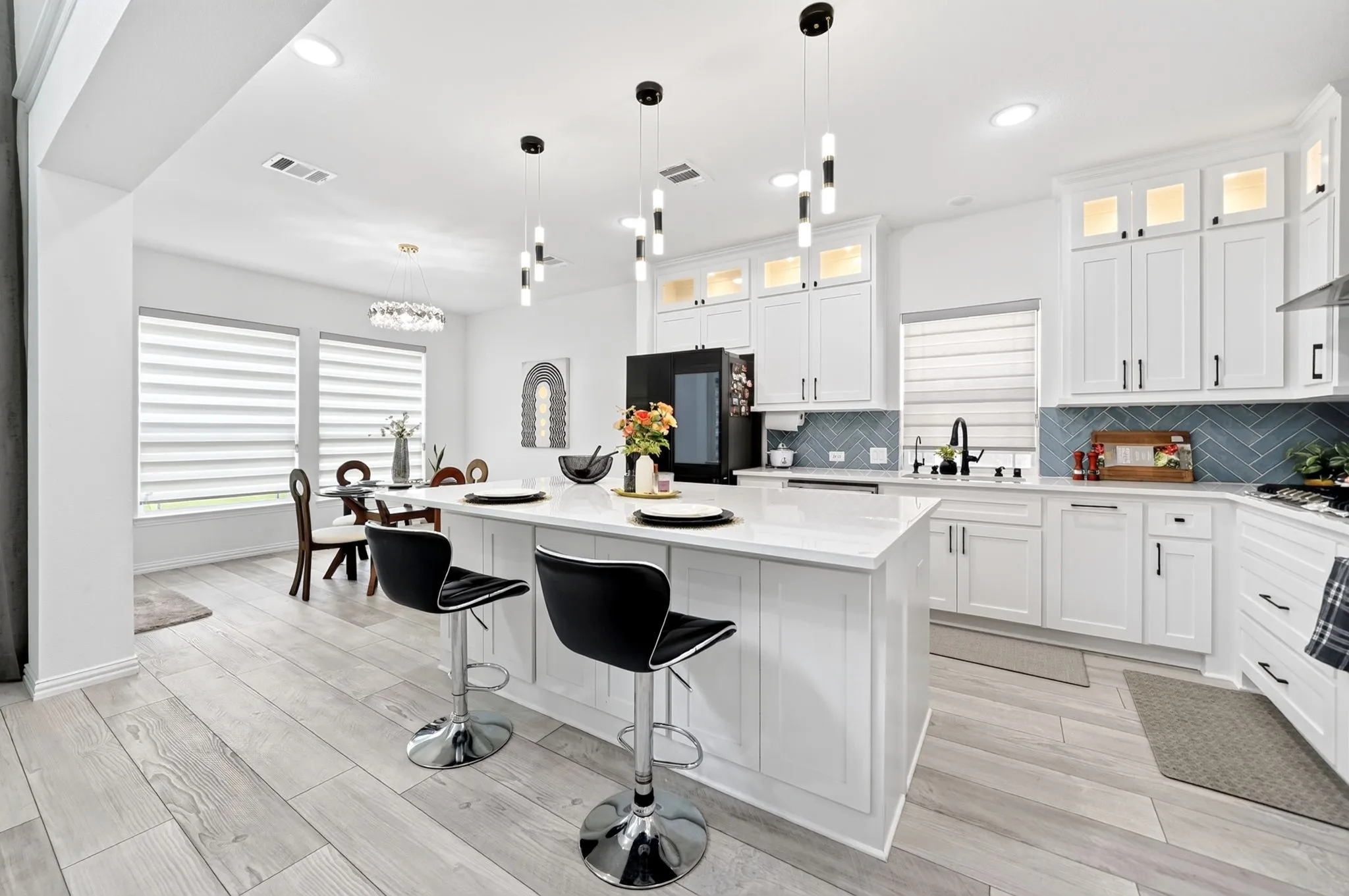 Bright kitchen featuring a central island with countertop seating, white cabinetry, herringbone tile backsplash, and light wood-finish flooring