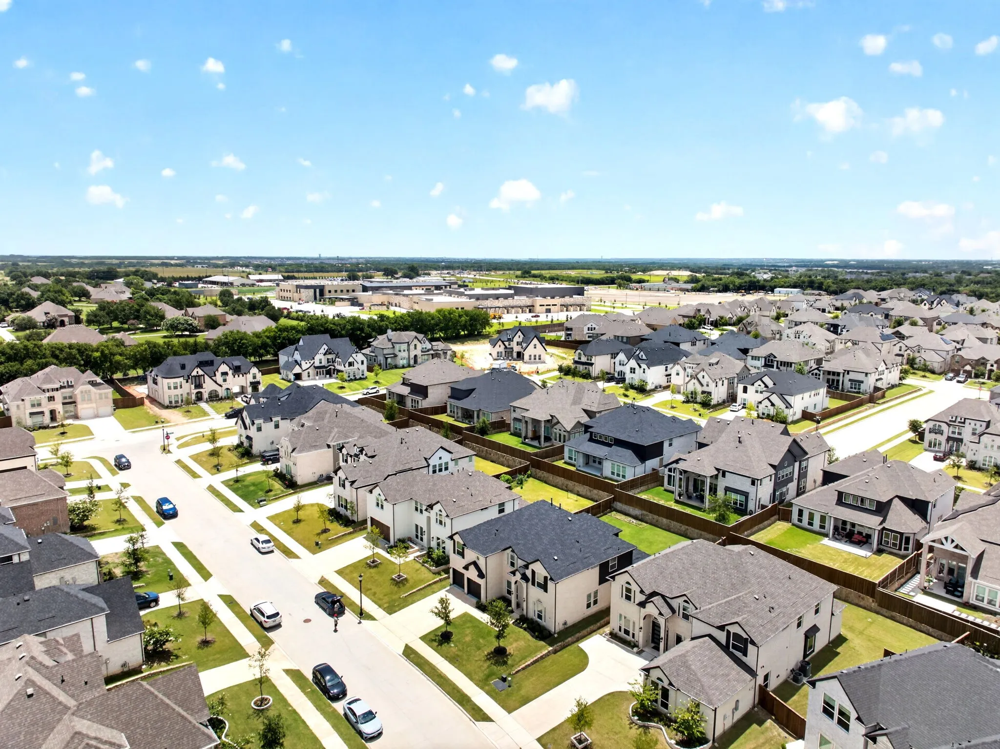 Neighborhood aerial showcasing residential properties with diverse architectural styles, manicured lawns, and paved streets