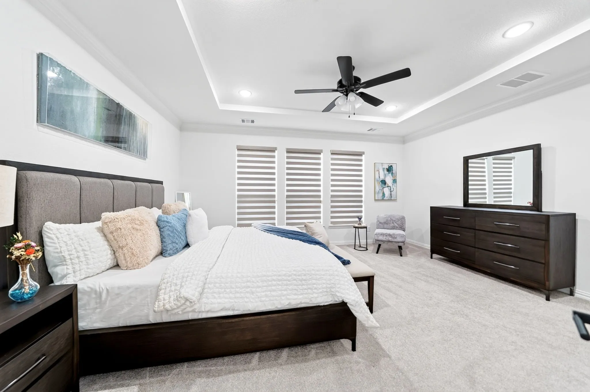 Spacious room featuring a tray ceiling with recessed lighting, crown molding, and a ceiling fan