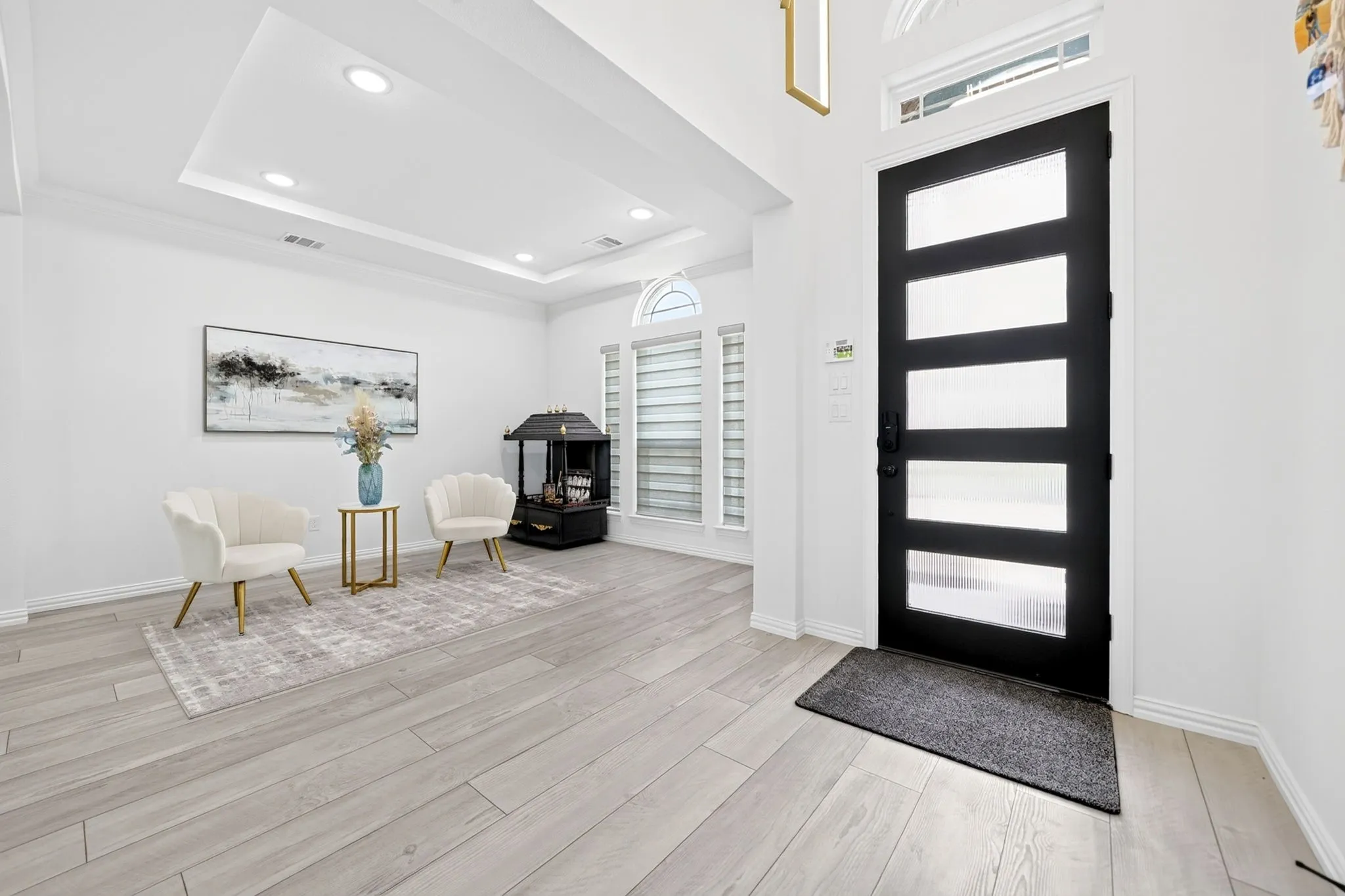 Entryway featuring a modern black door with frosted glass panels, transom window, recessed lighting, and wood-finish flooring