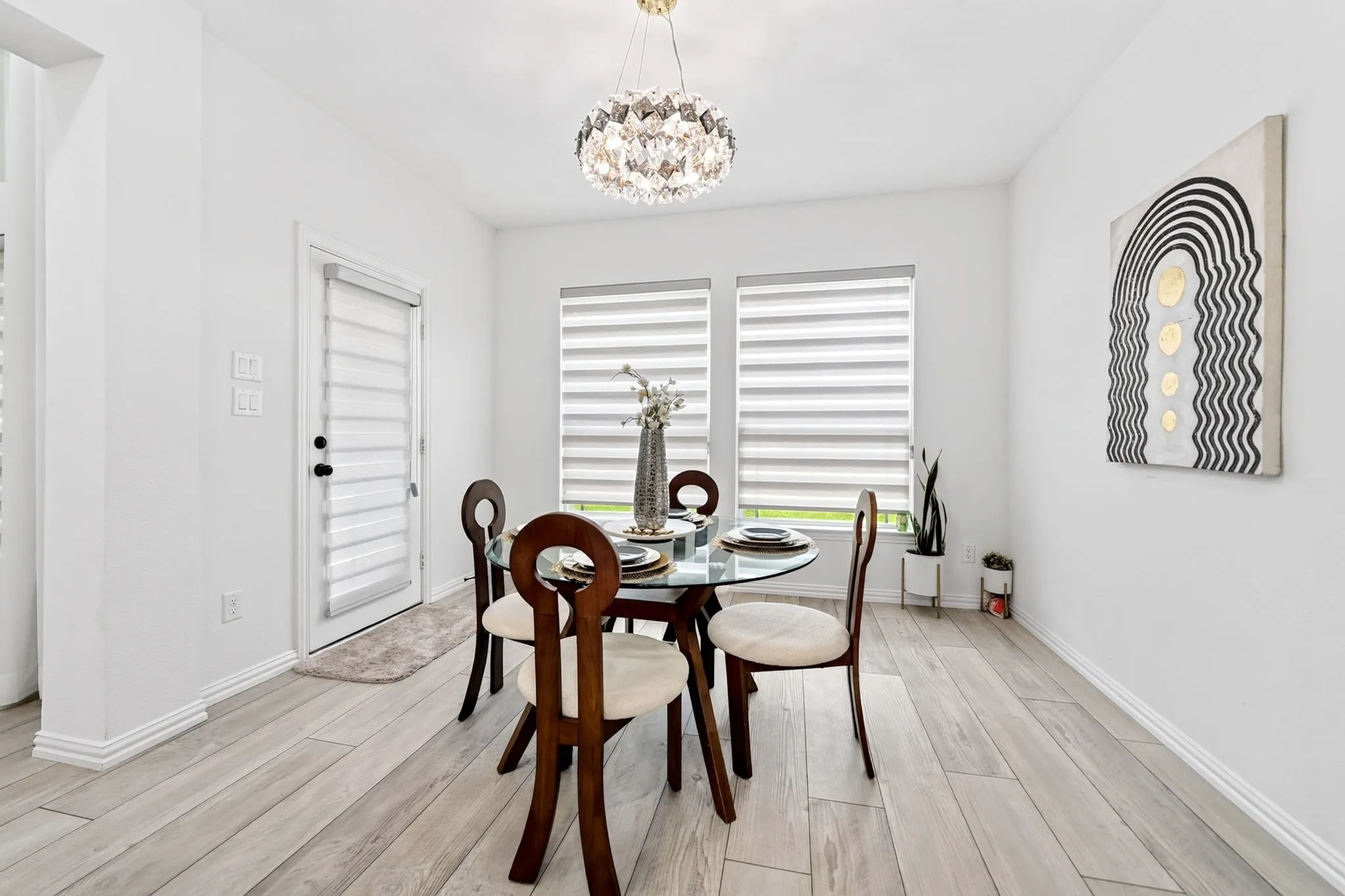 Dining area featuring wood-finish flooring, a contemporary crystal chandelier, and two windows with horizontal blinds