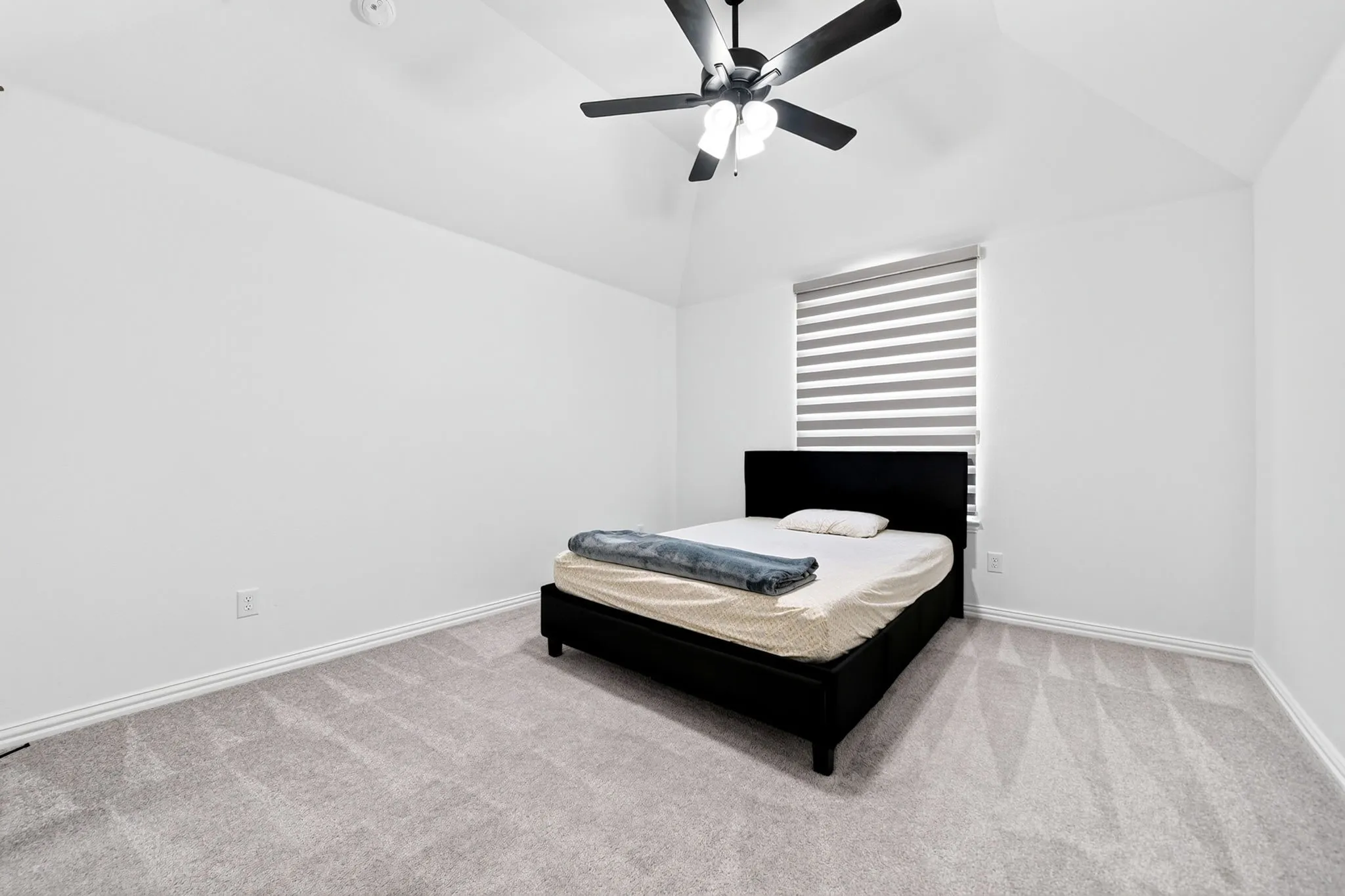 Room featuring a vaulted ceiling and a contemporary ceiling fan with integrated lighting