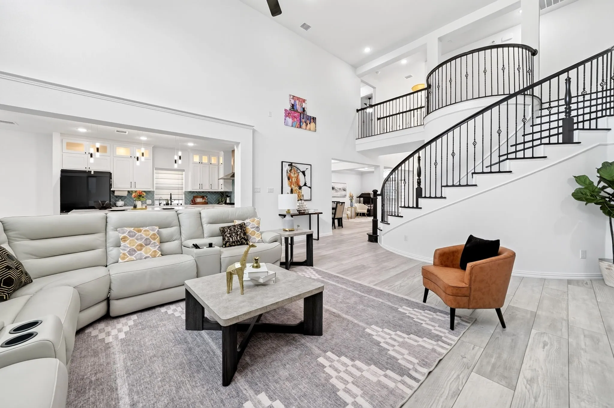 Grand living area featuring a sweeping curved staircase with wrought iron balusters