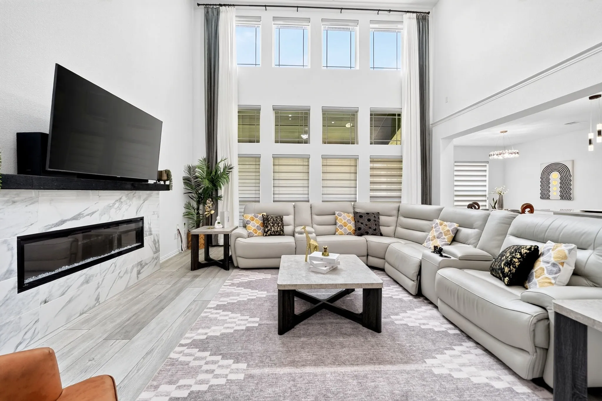 Two-story living area featuring a marble-style fireplace surround, linear electric fireplace, and high ceilings