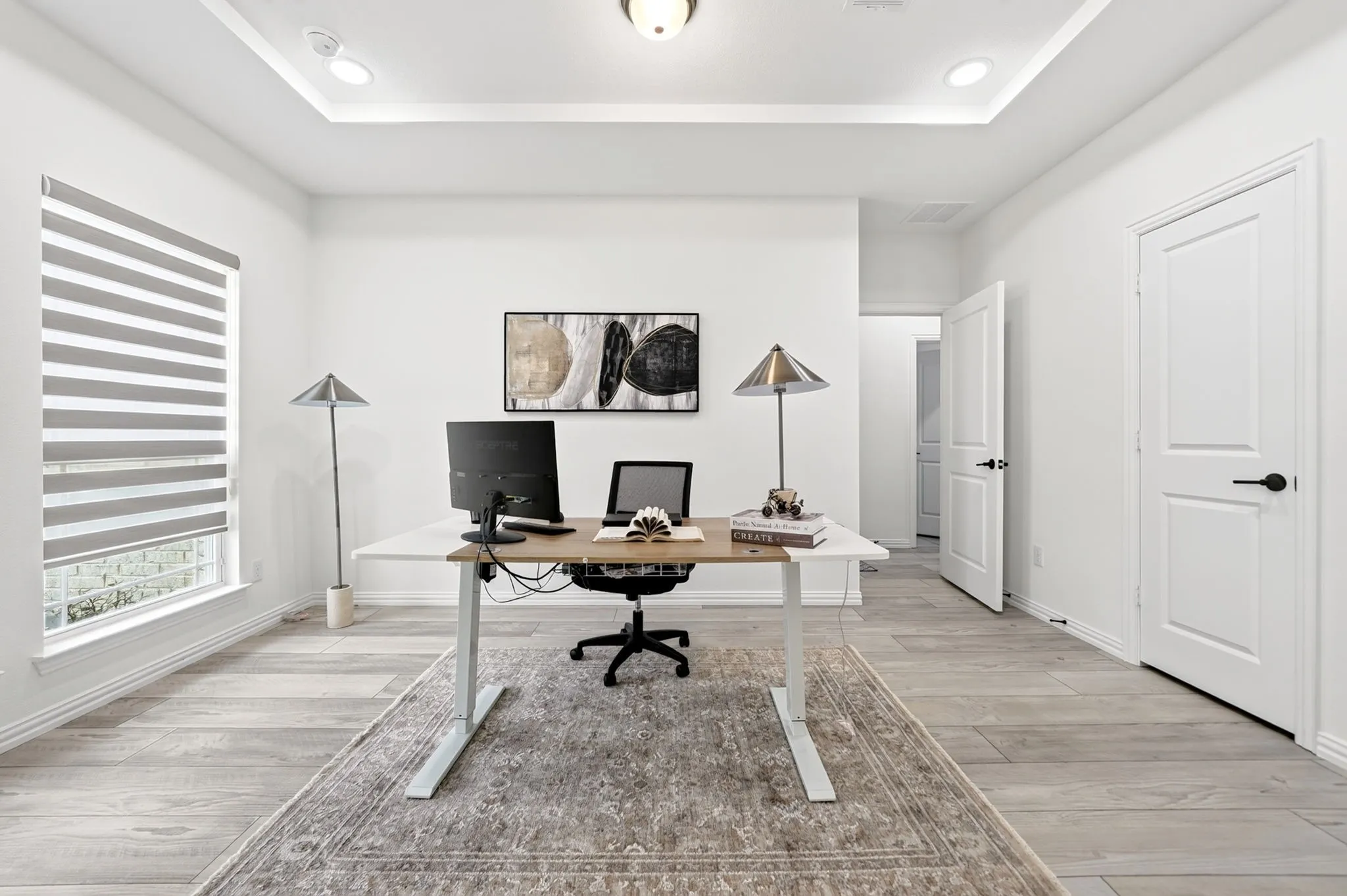 Spacious room featuring wood-finish flooring, a tray ceiling with recessed lighting, and a large window with privacy blinds