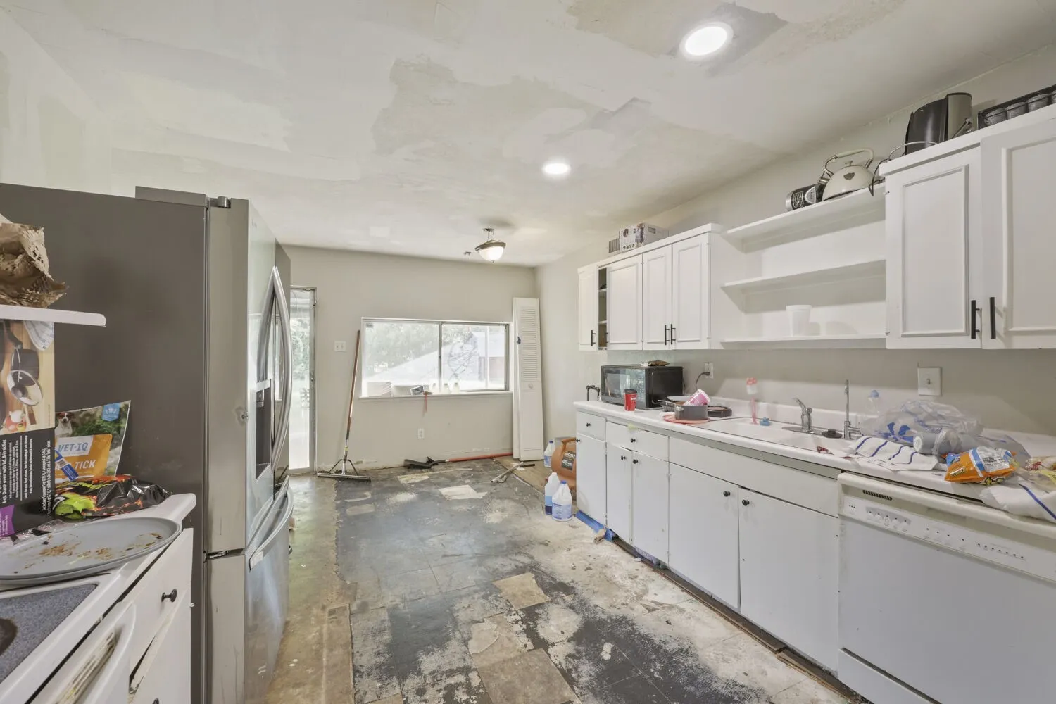 Kitchen space featuring white cabinetry with dark hardware, a stainless steel refrigerator, and recessed lighting