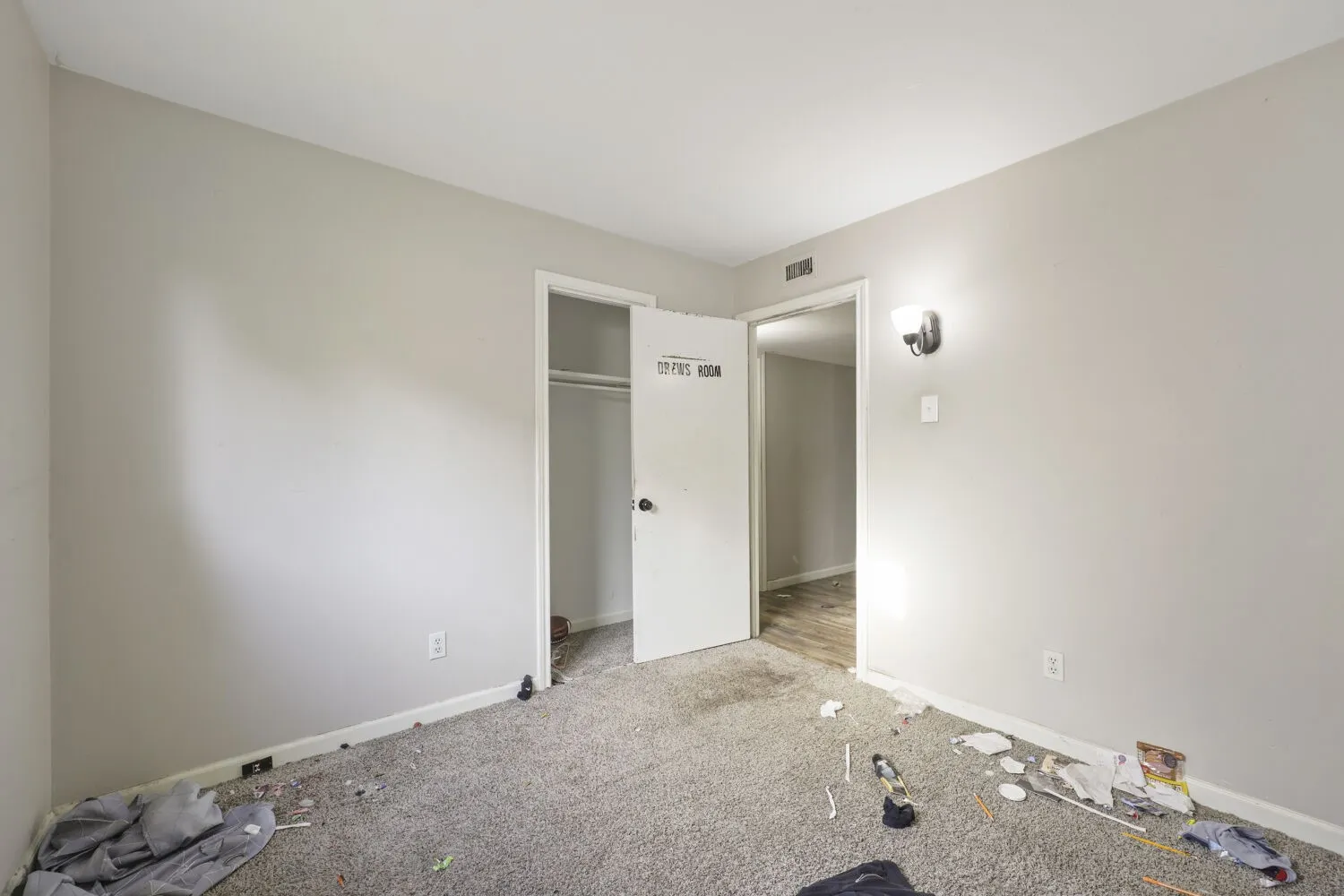 Room featuring light gray walls, gray carpeting, a single wall-mounted light fixture, and two doorways