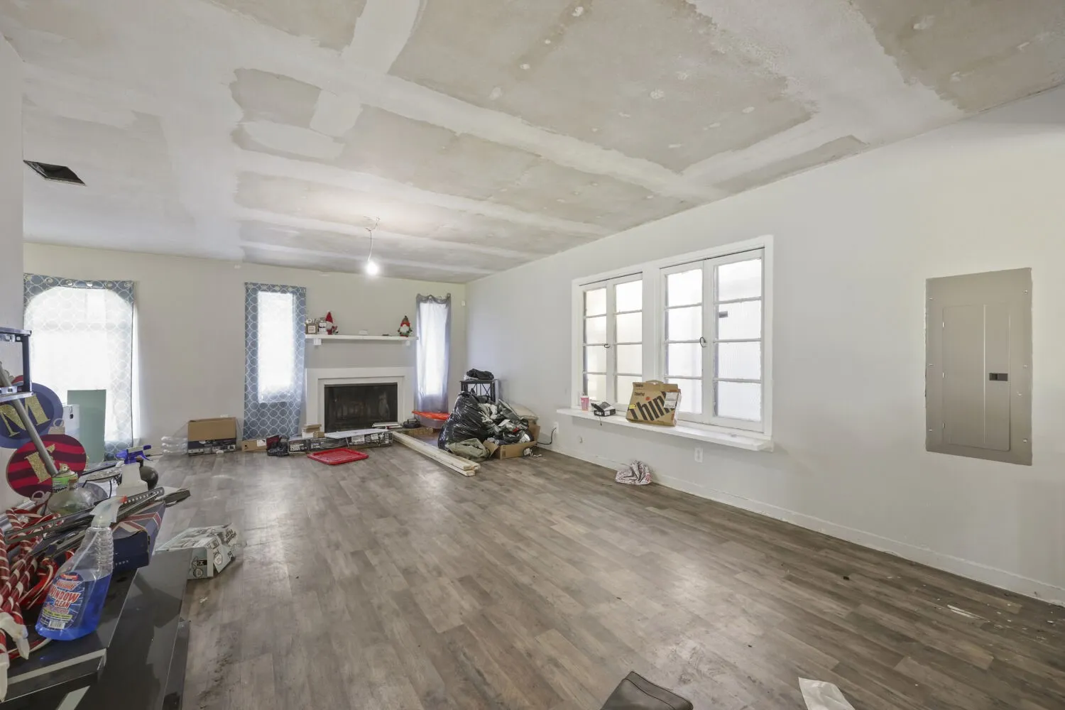 Spacious interior featuring wood-finish flooring, a fireplace with a white mantel, and white walls