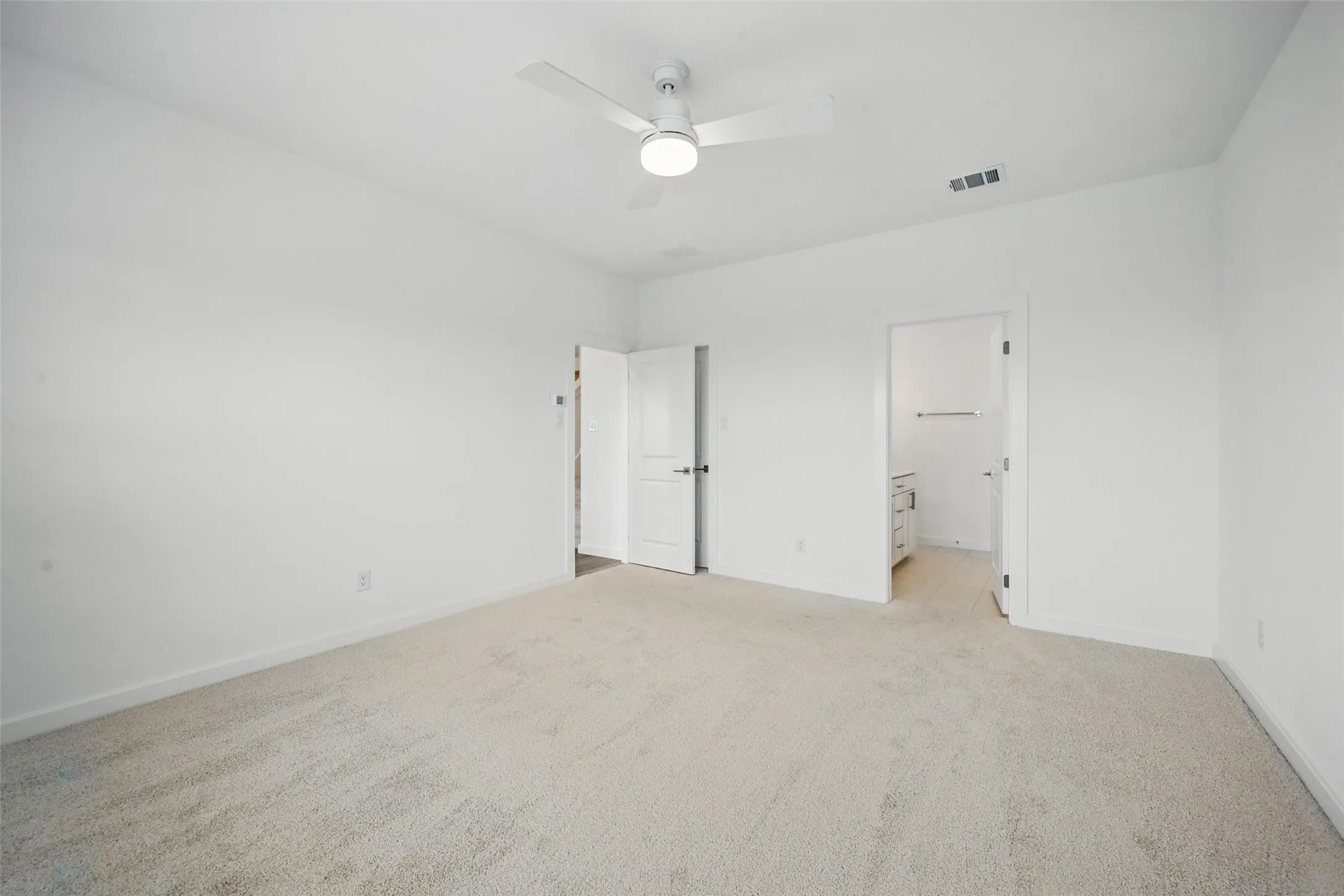 Carpeted room with white walls, featuring a ceiling fan and recessed lighting