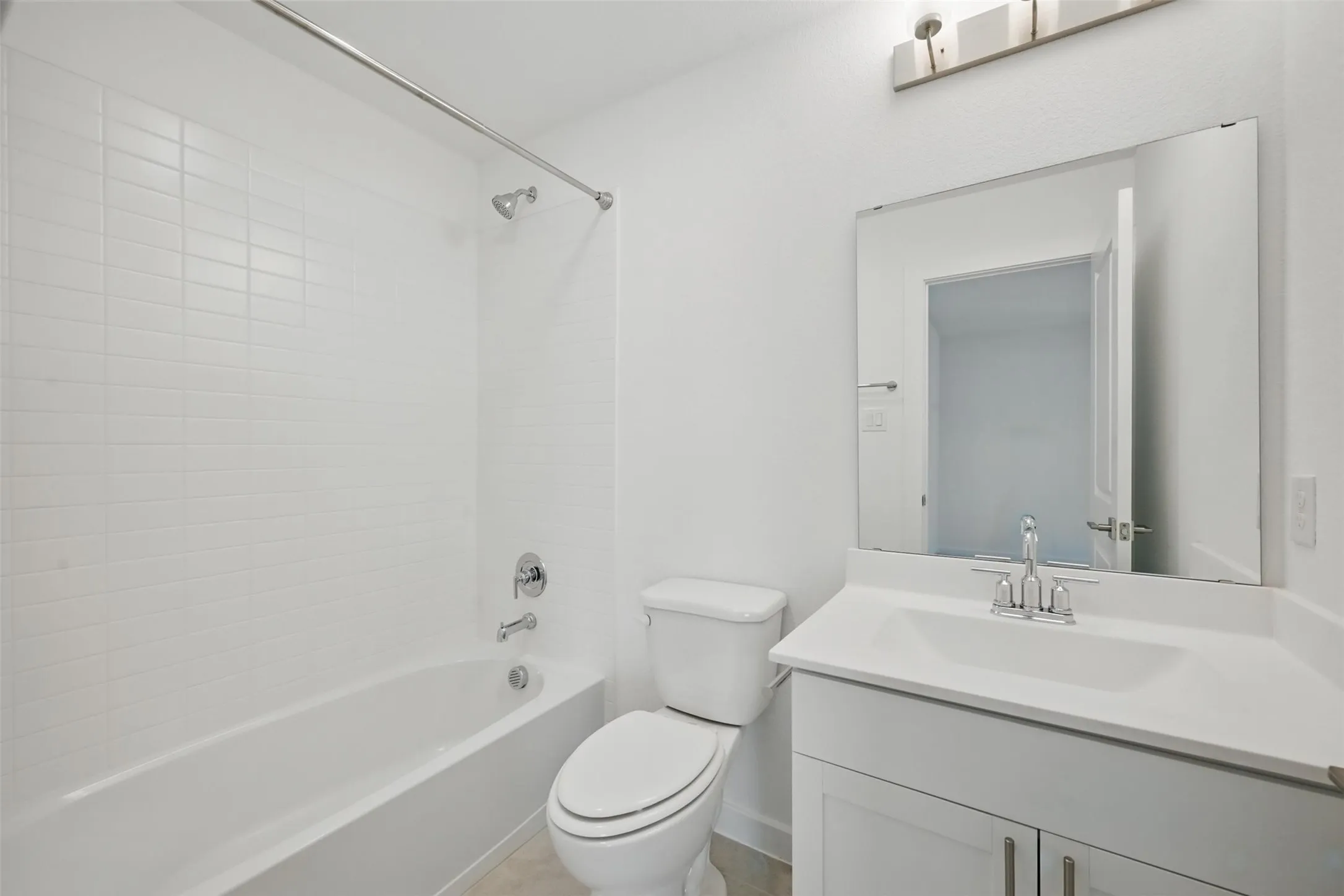Bathroom with white subway tile shower surround, chrome fixtures, a white vanity with integrated sink, and a framed mirror