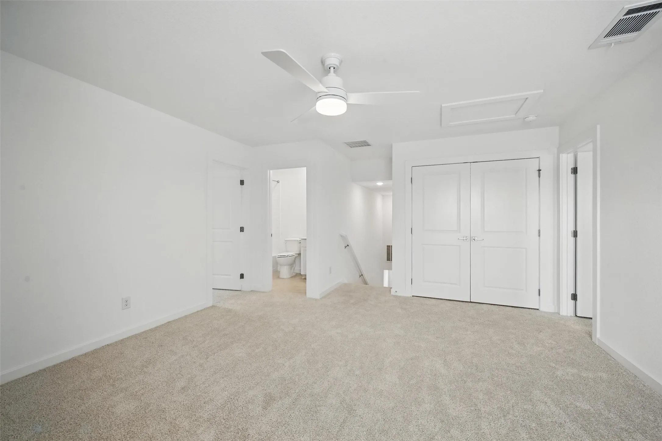Spacious room featuring neutral carpet, a contemporary ceiling fan, and crisp white walls