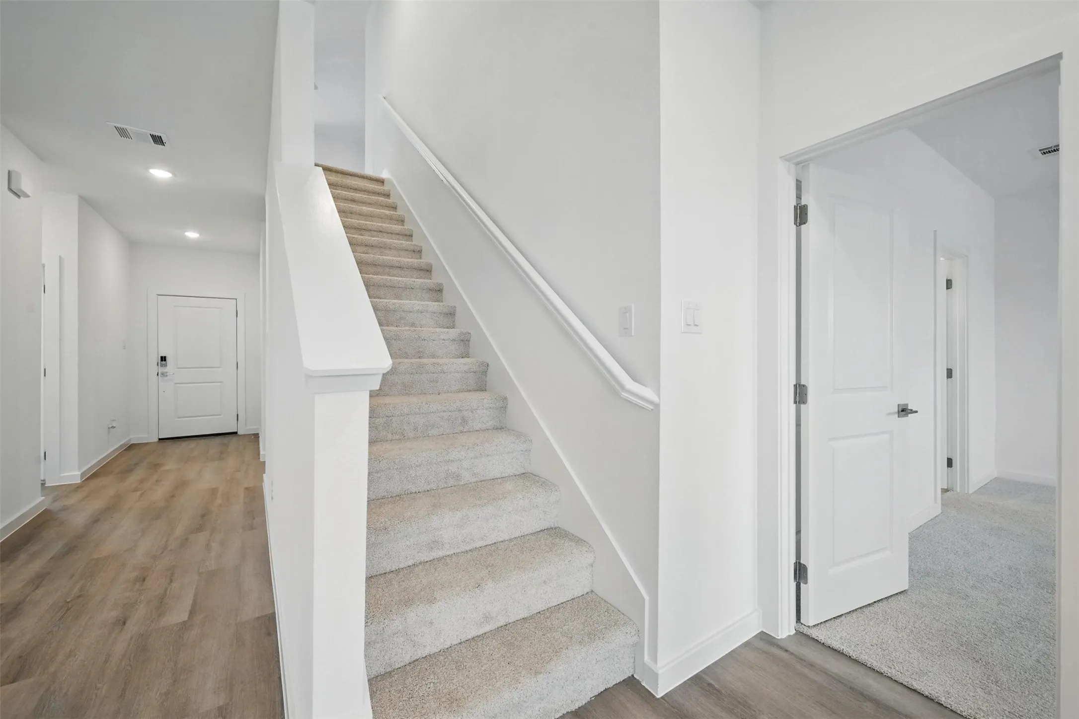 Modern staircase with carpeted treads and a painted handrail