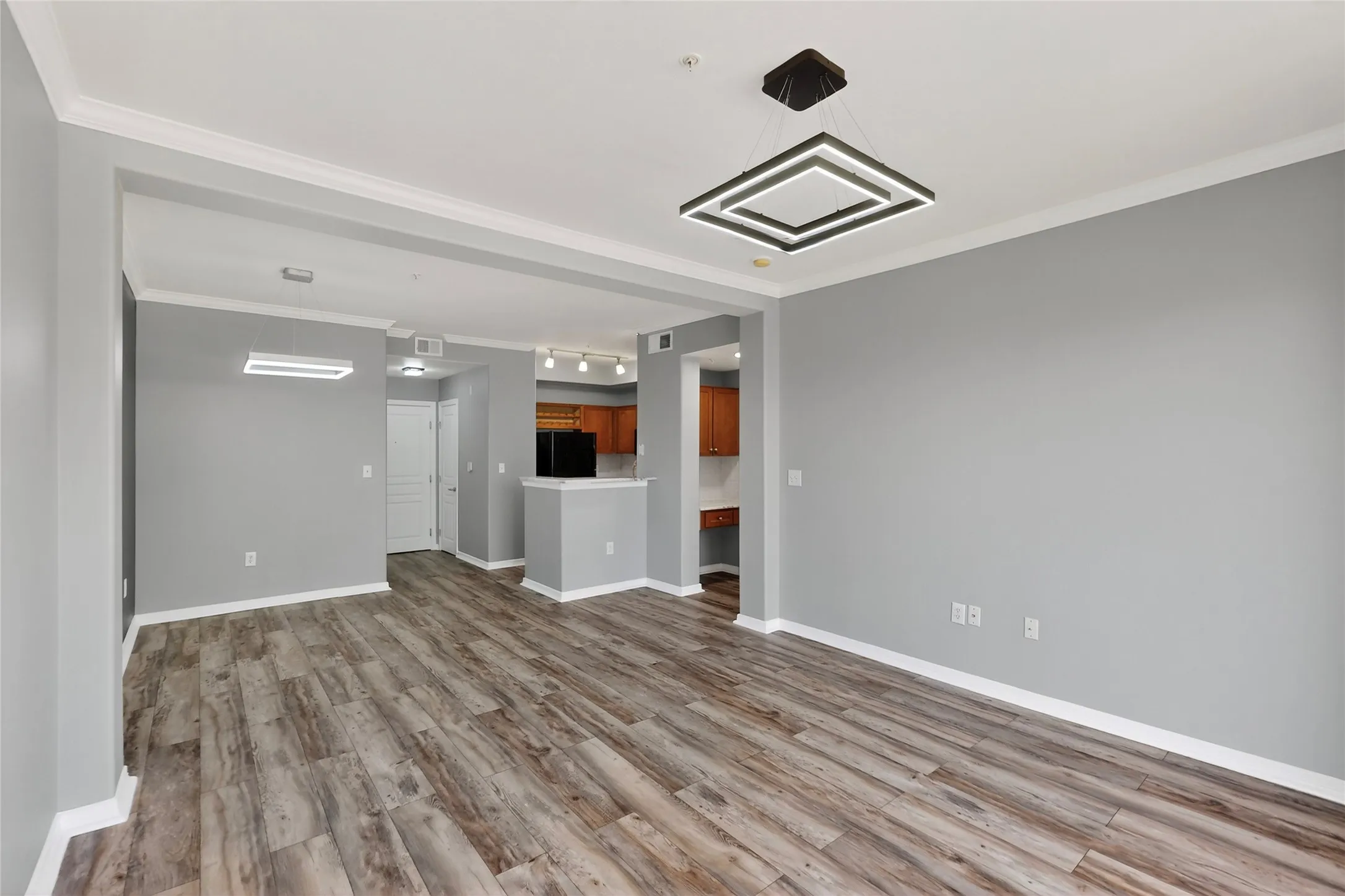 Unfurnished living room with wood finished floors and crown molding