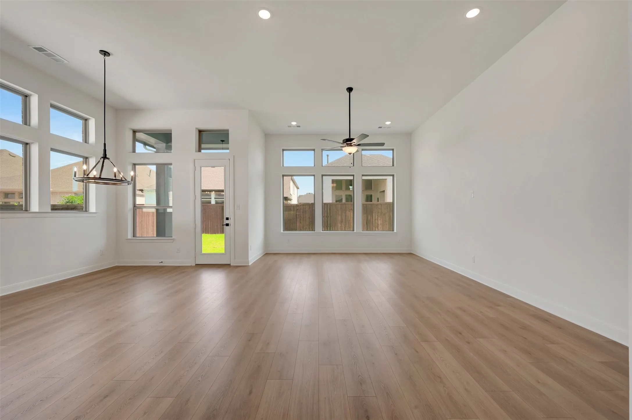 Spacious room featuring wood-finish flooring, numerous windows, and high ceilings with recessed lighting